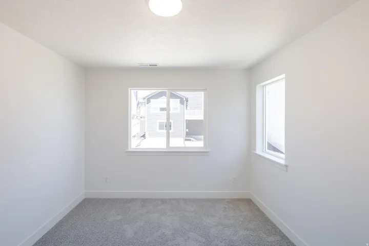 Neutral-toned room featuring a large double window and an additional single window