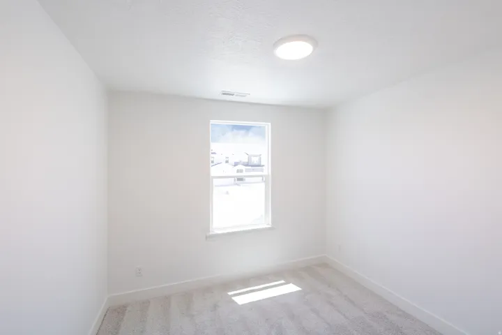 Bright room featuring a single window, recessed lighting, white walls, white trim, and gray carpet