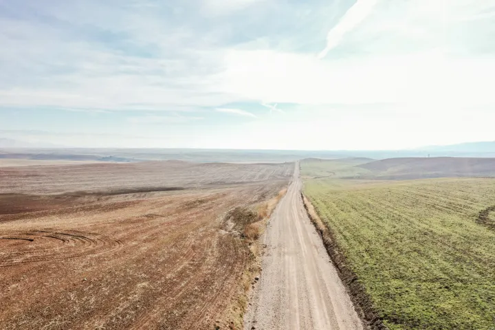 View of dirt / gravel road featuring a view of countryside and a mountain view
