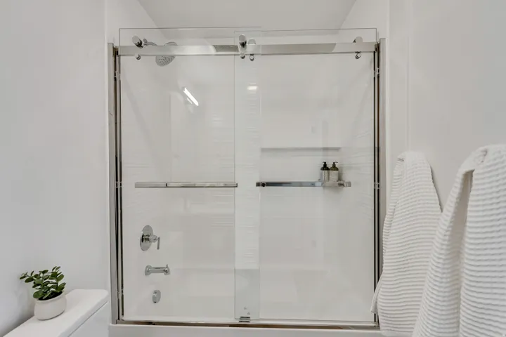 Bathroom with toilet and combined bath / shower with glass door