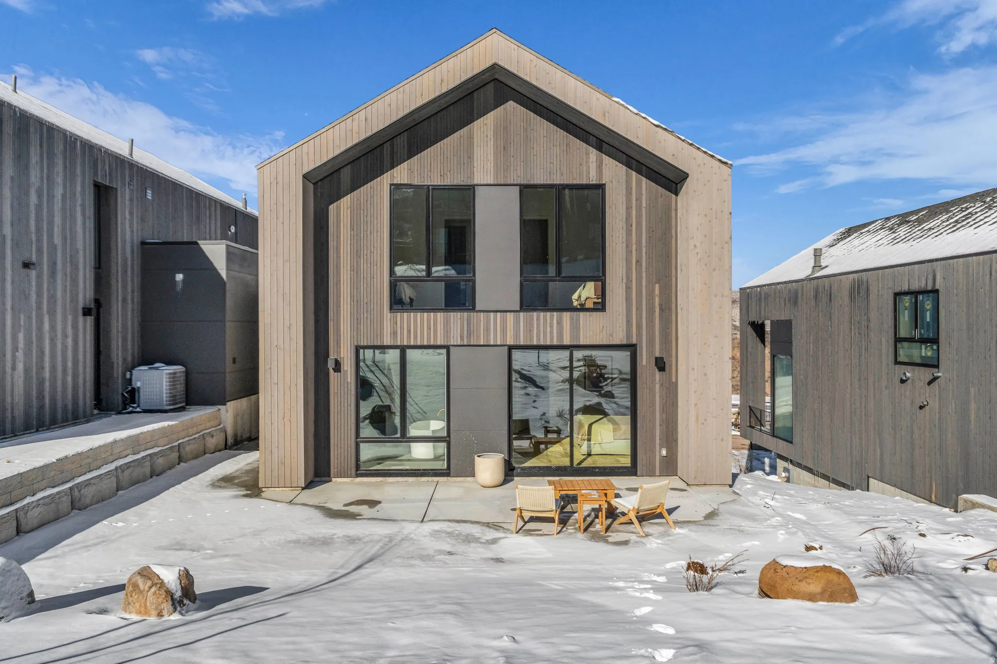 Snow covered back of property with a patio