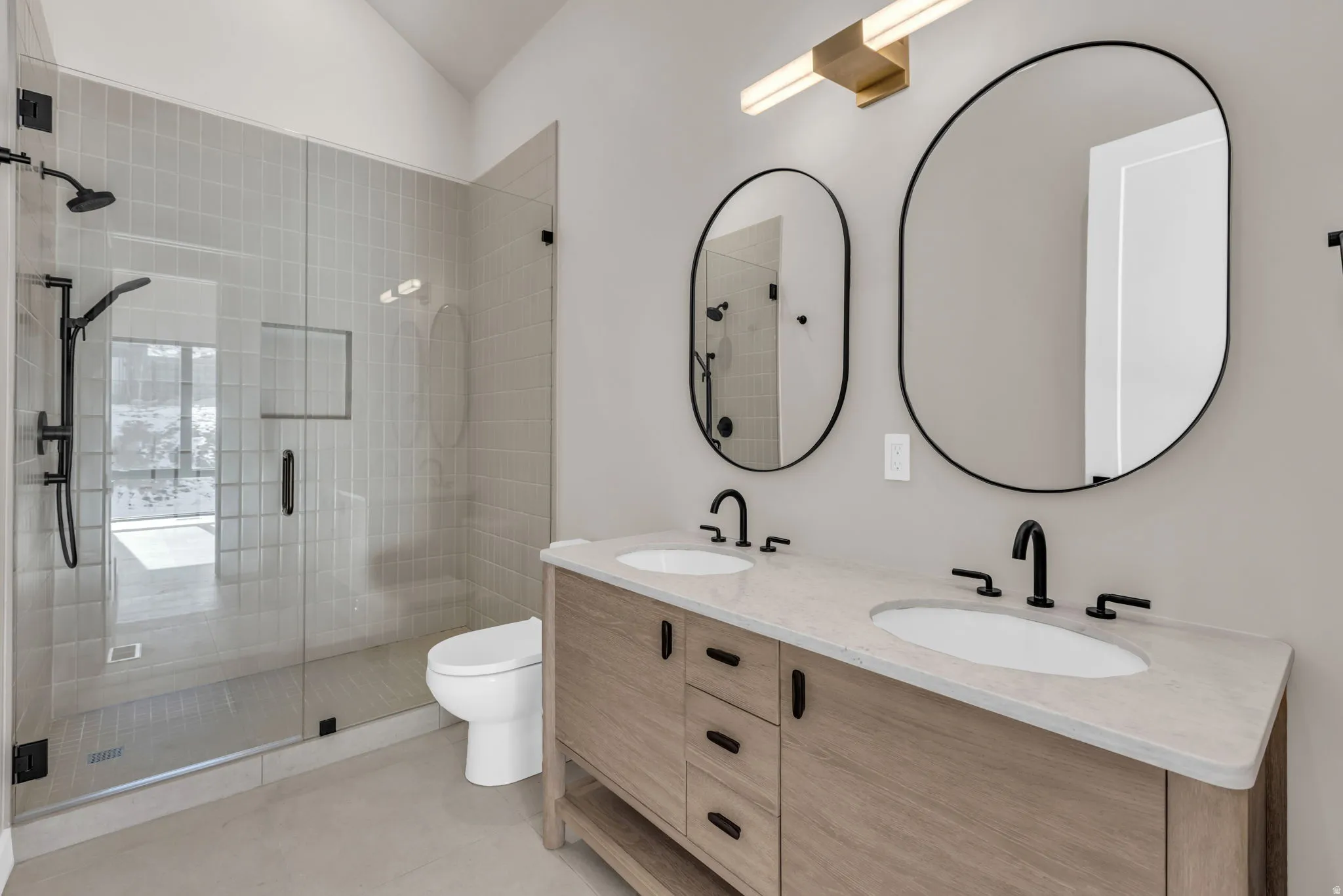 Bathroom featuring double vanity, a shower stall, and light tile patterned floors