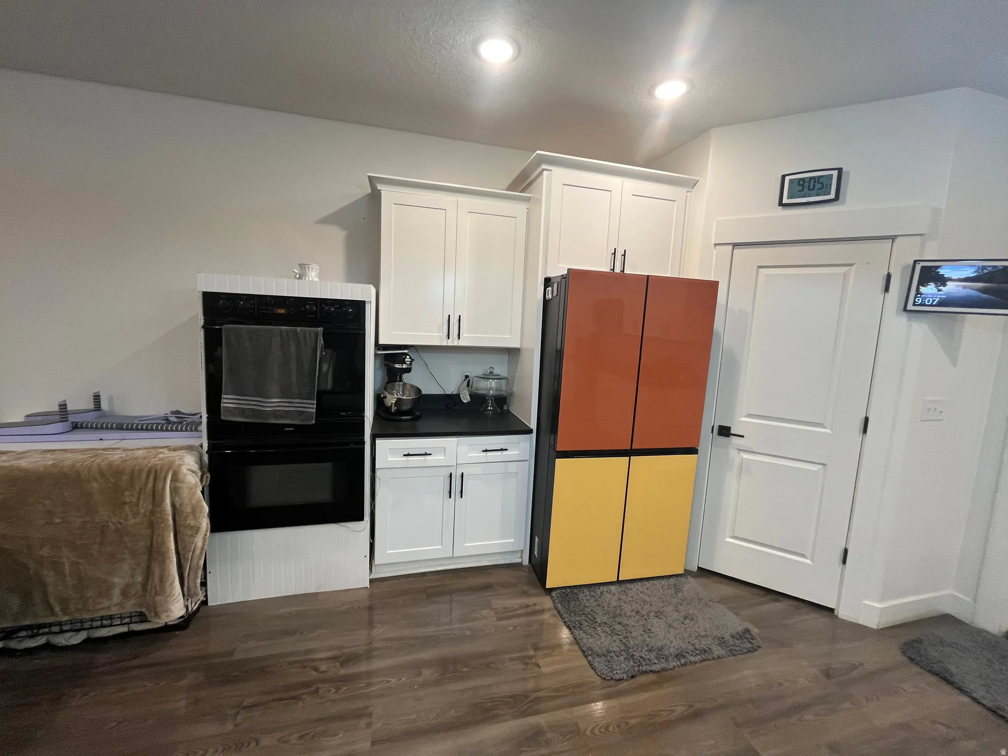 Kitchen with white cabinets, dark countertops, dark wood-style flooring, and freestanding refrigerator