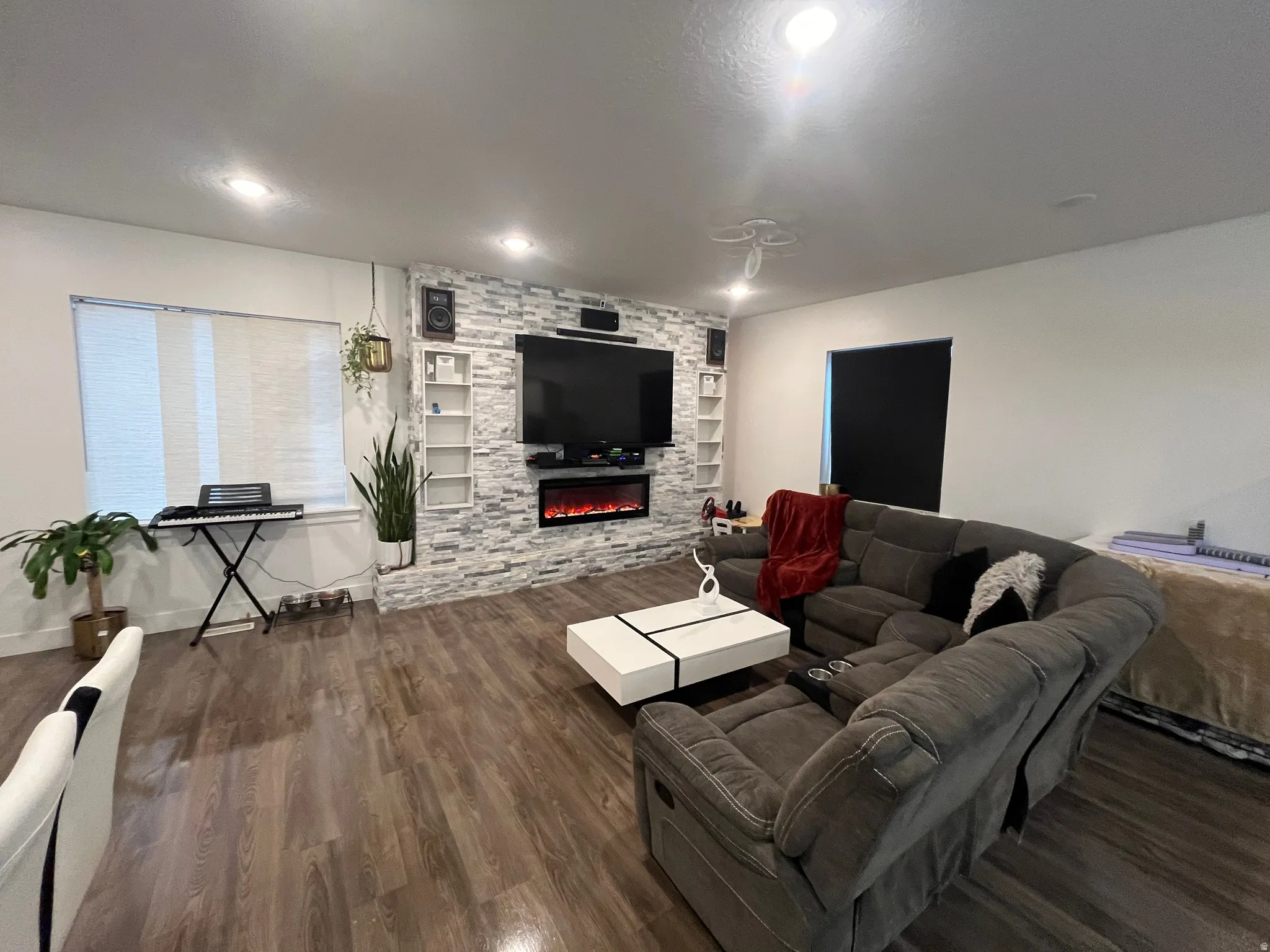 Living area featuring dark wood-style flooring, built in features, a stone fireplace, and recessed lighting