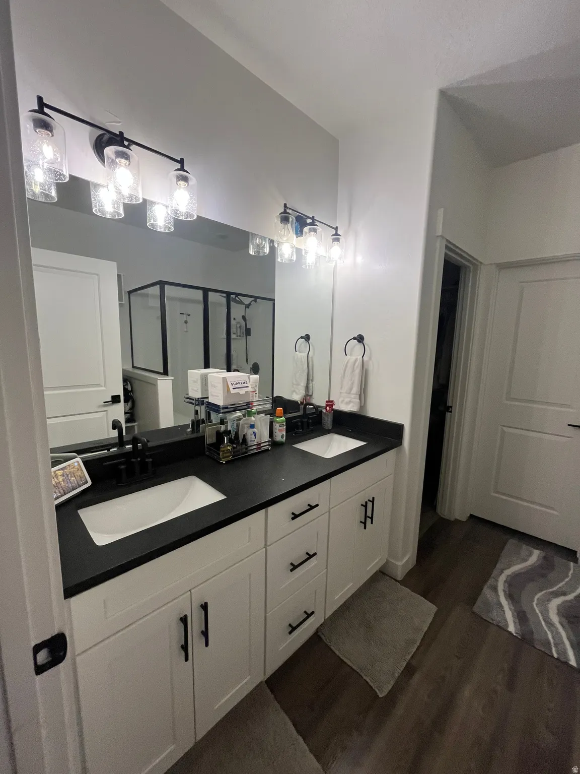 Master bath- Full bathroom with a shower stall, double vanity, and dark wood finished floors