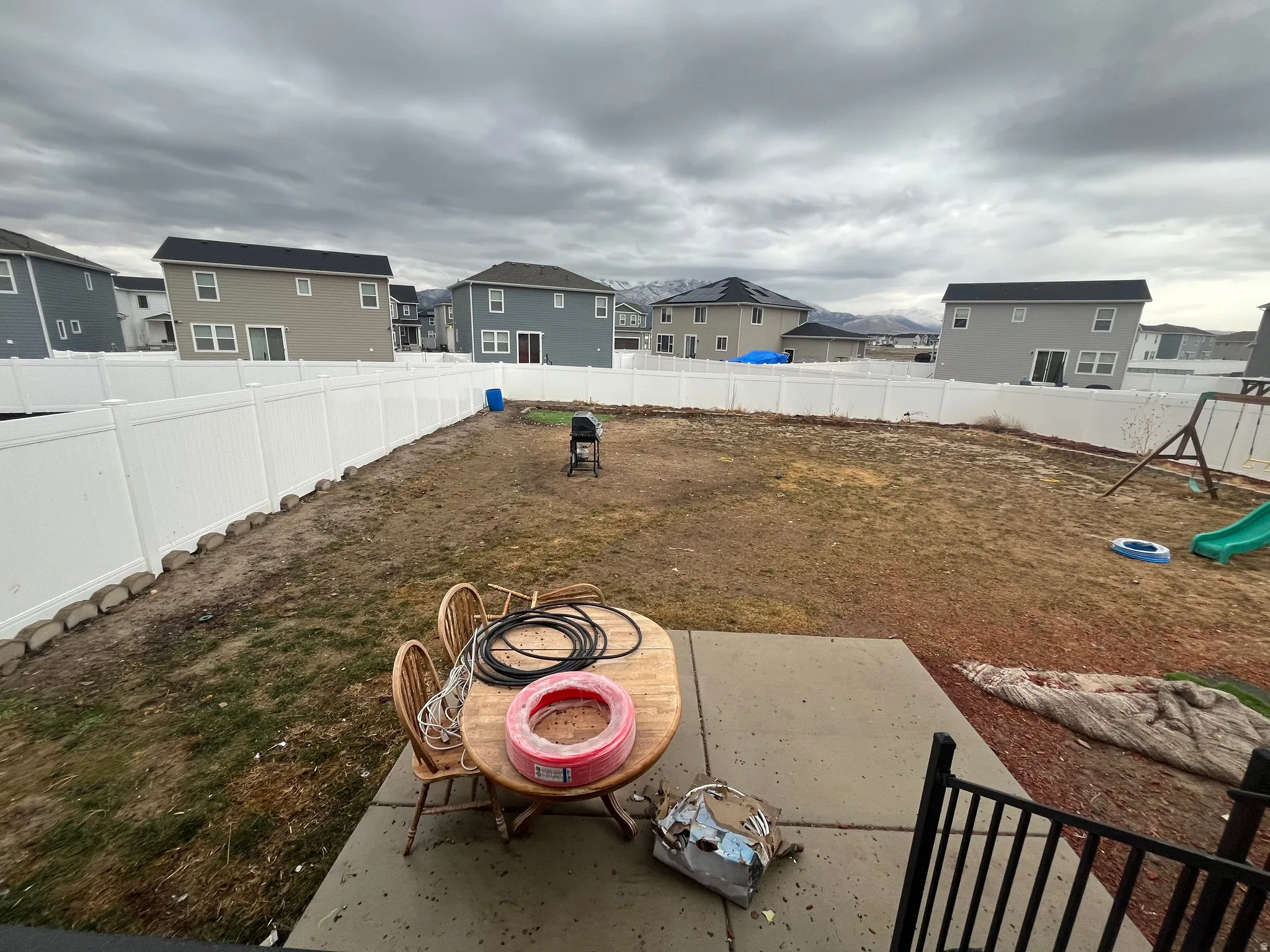 Fenced backyard with a residential view, a playground, and a patio