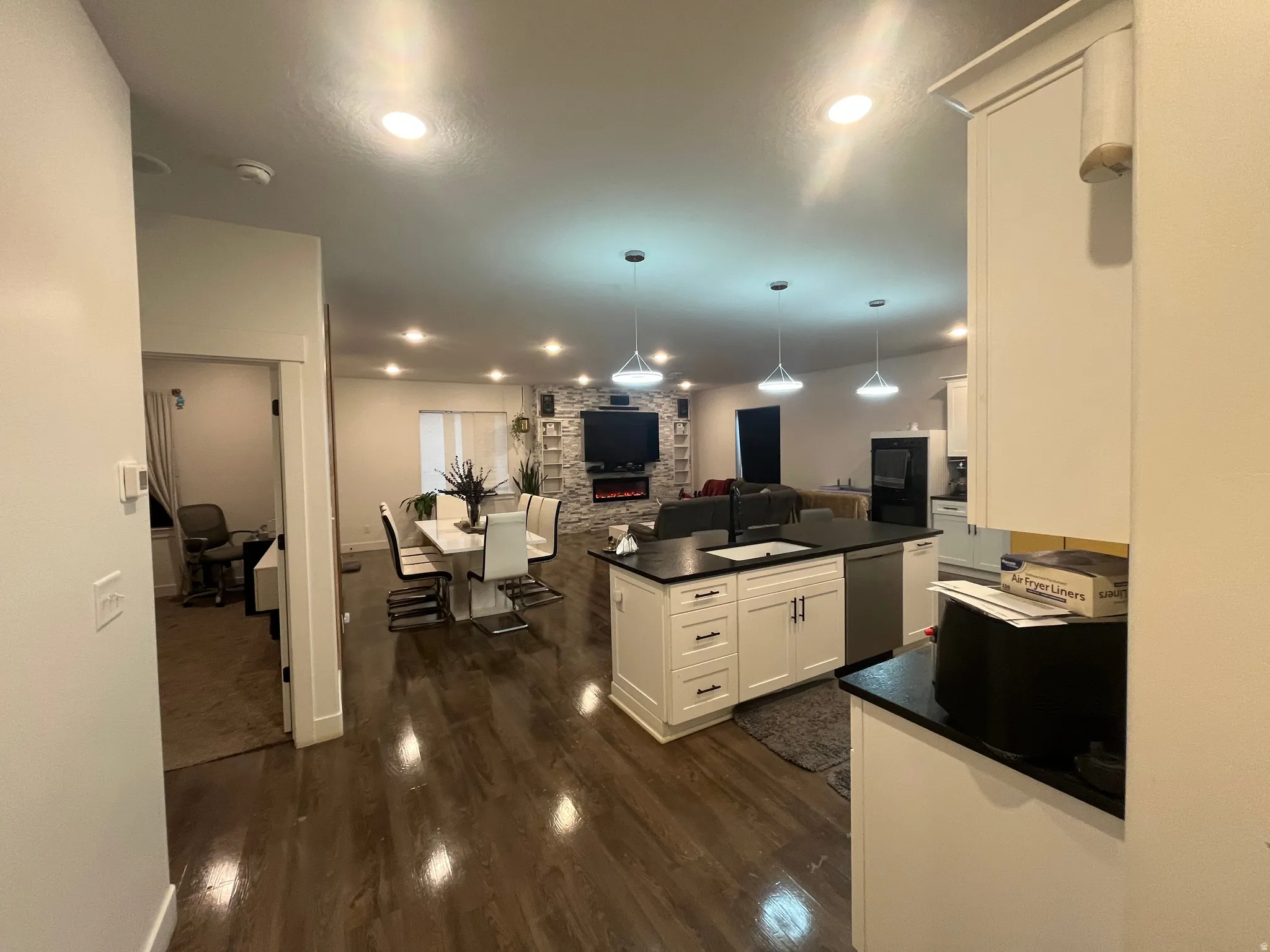 Kitchen with open floor plan, white cabinets, hanging light fixtures, and dark wood-style floors