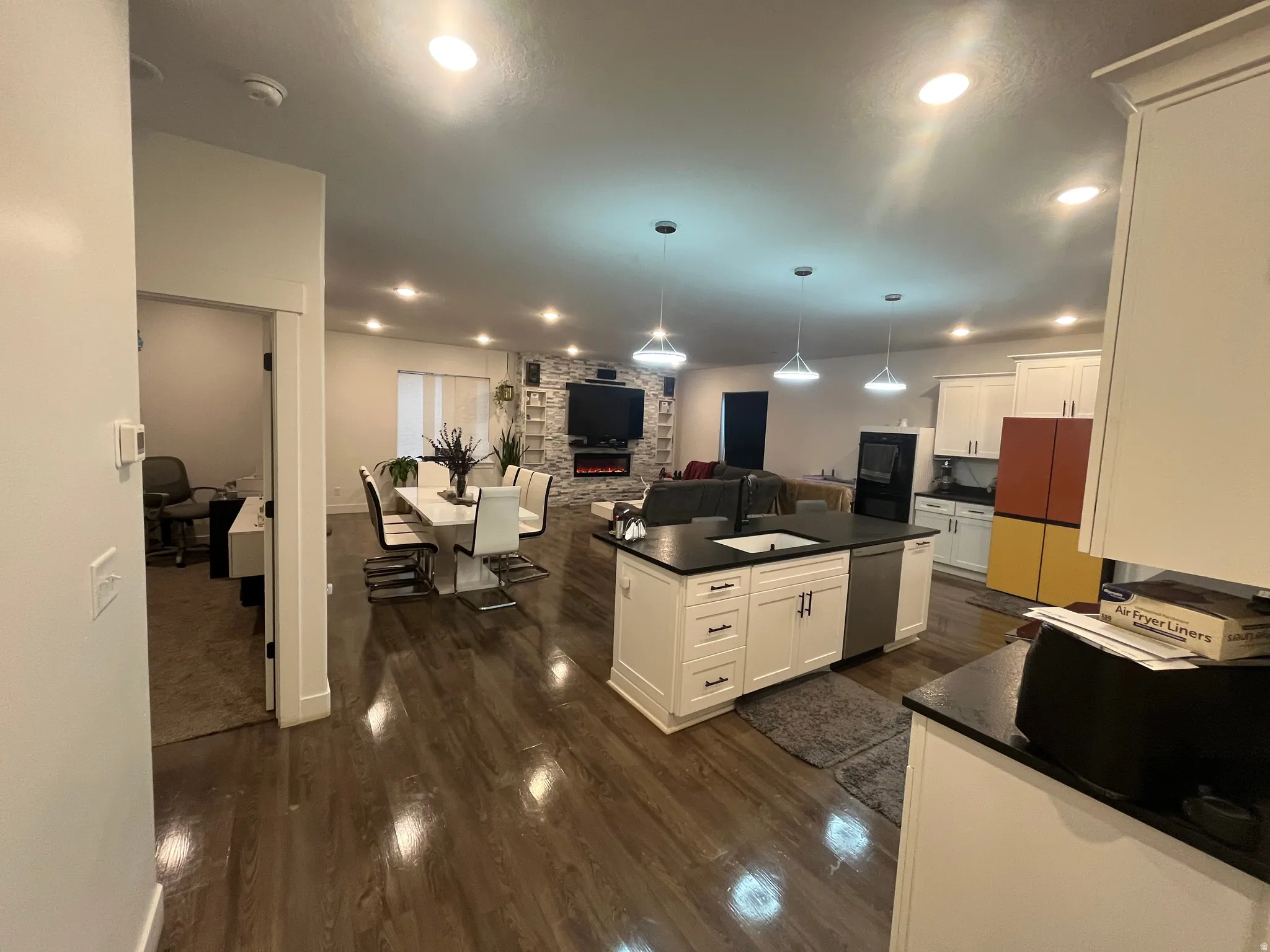 Kitchen featuring open floor plan, pendant lighting, dark wood finished floors, white cabinets, and fridge