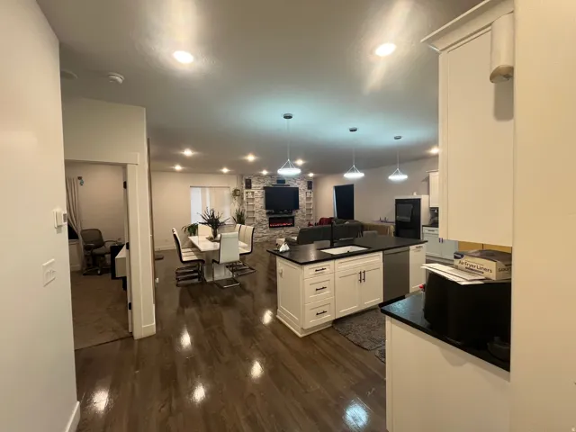 Kitchen with open floor plan, white cabinets, hanging light fixtures, and dark wood-style floors