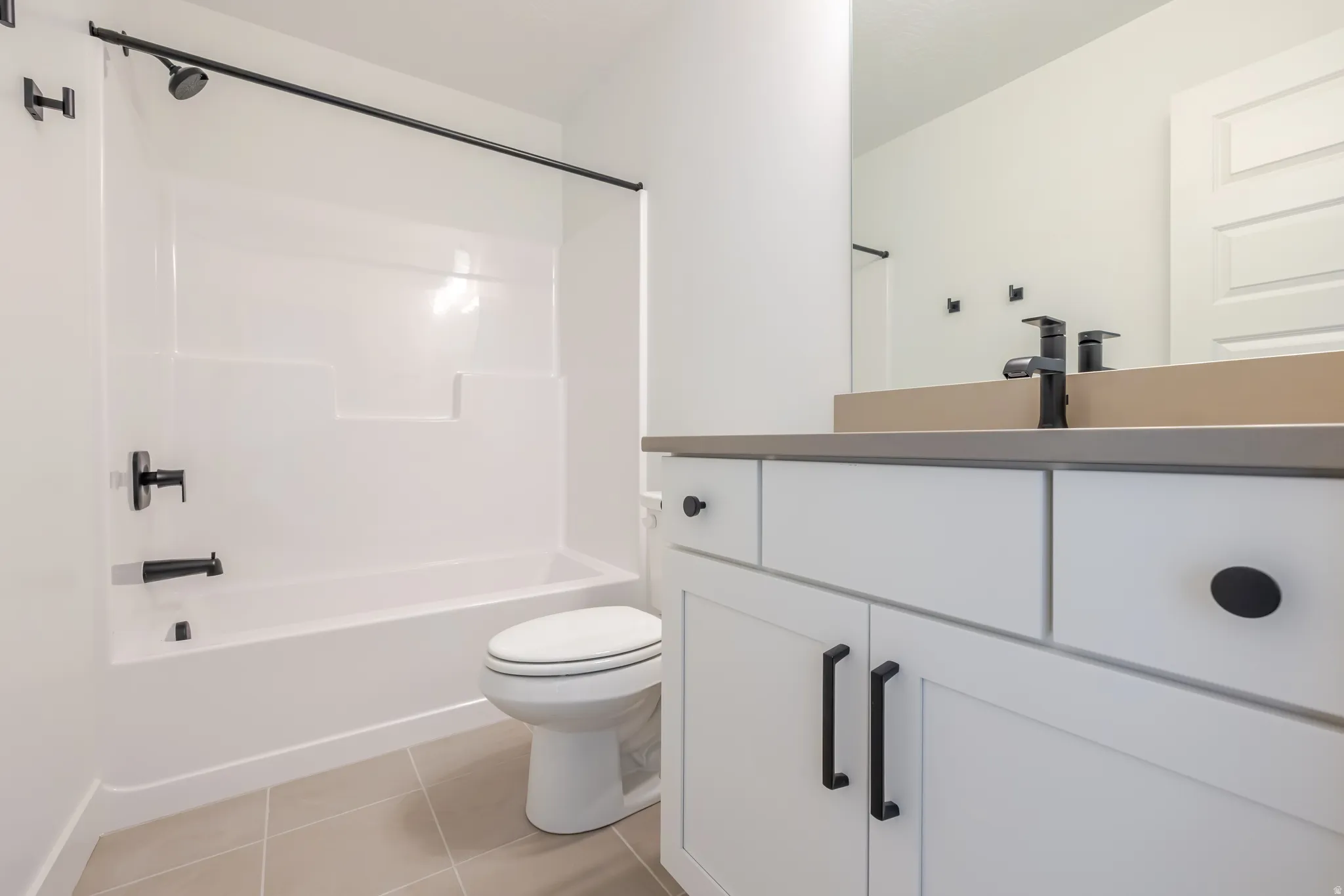 Clean-lined bathroom featuring a white vanity with matte black hardware, a rectangular undermount sink, and a contrasting countertop