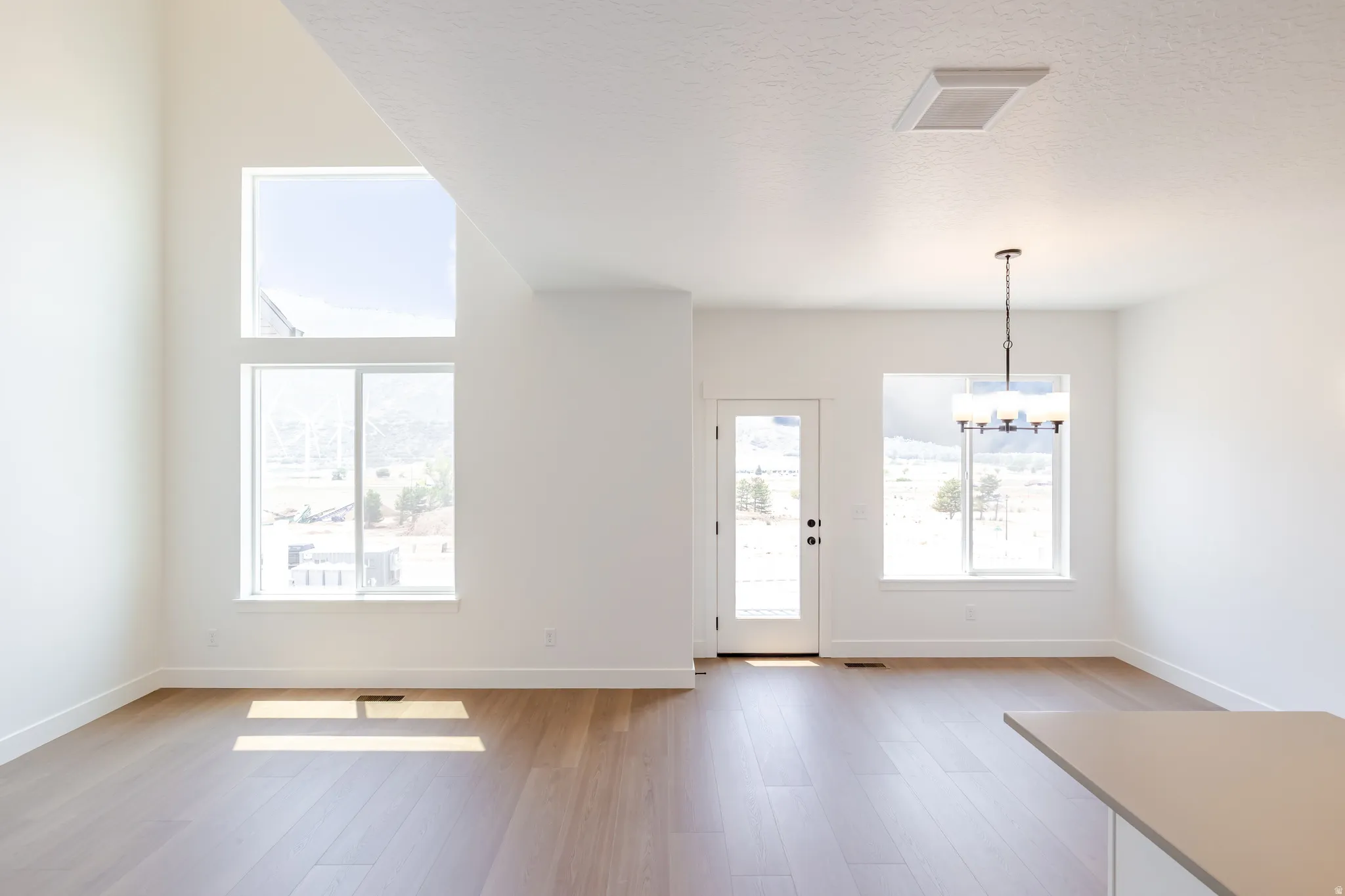 Vaulted ceiling living space featuring a floor-to-ceiling window arrangement and wood-finish flooring