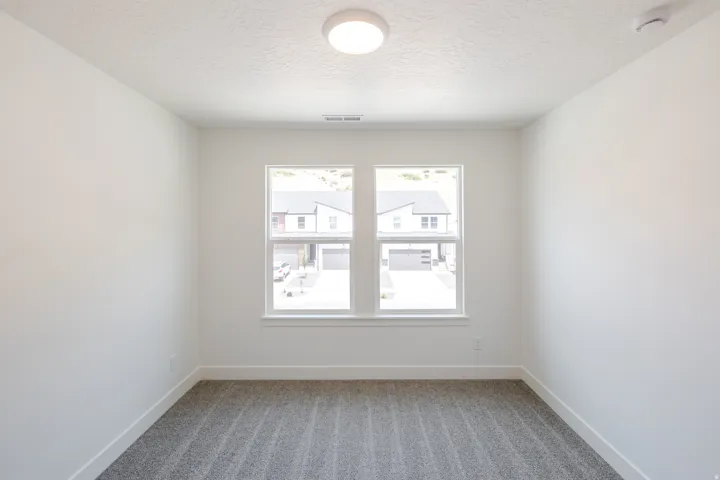 Room featuring two double-hung windows with white trim, a recessed ceiling light fixture, and textured carpet flooring