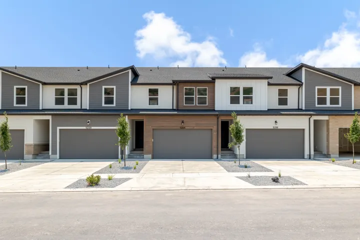 Modern townhome exteriors featuring varied siding, multiple window configurations, and attached garages