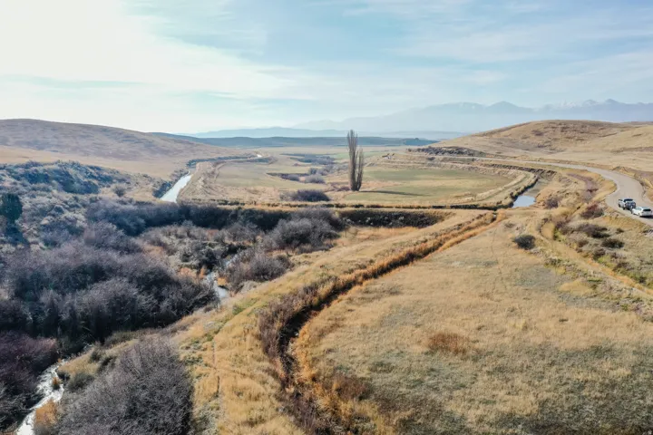 Aerial view of property and surrounding area featuring a mountainous background and rural landscape