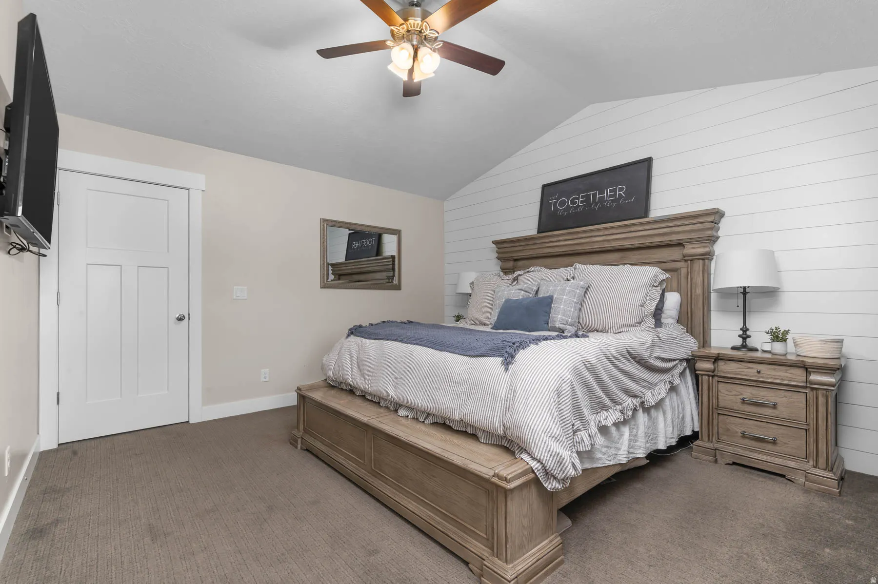 Carpeted bedroom with wood walls and ceiling fan