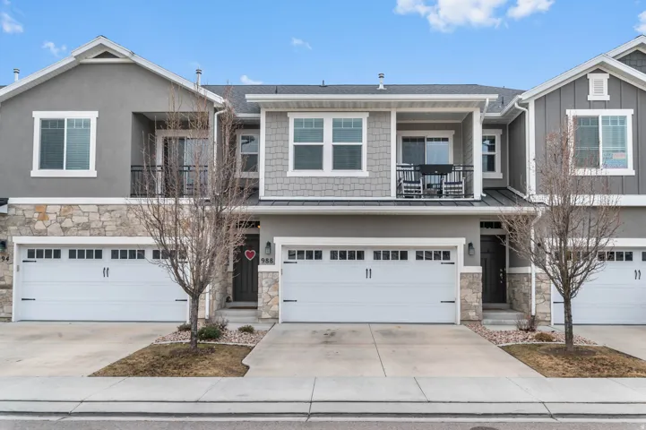 Craftsman house with stone siding, a balcony, an attached garage, and driveway