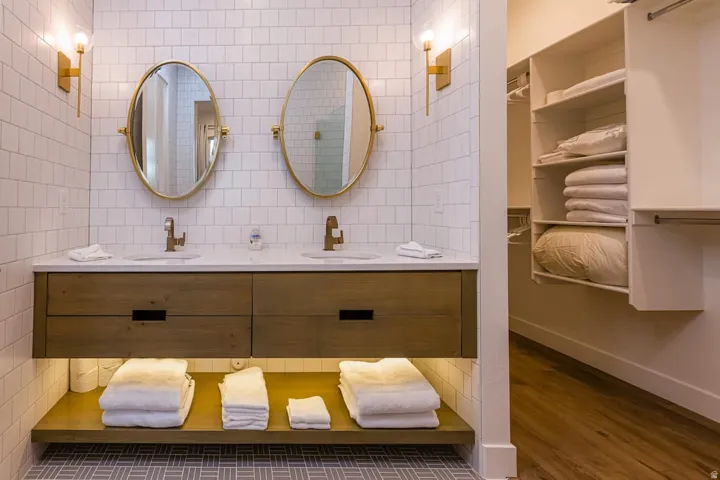 Full bathroom with double vanity, dark wood finished floors, backsplash, a spacious closet, and tile walls