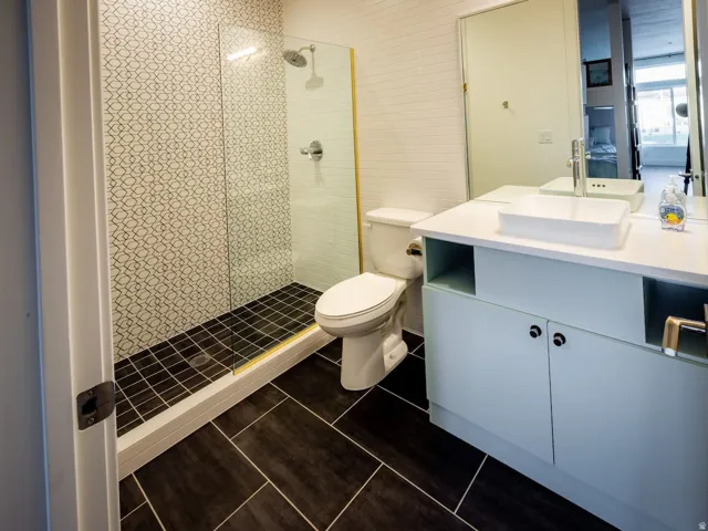 Bathroom featuring vanity, tiled shower, and dark tile patterned flooring