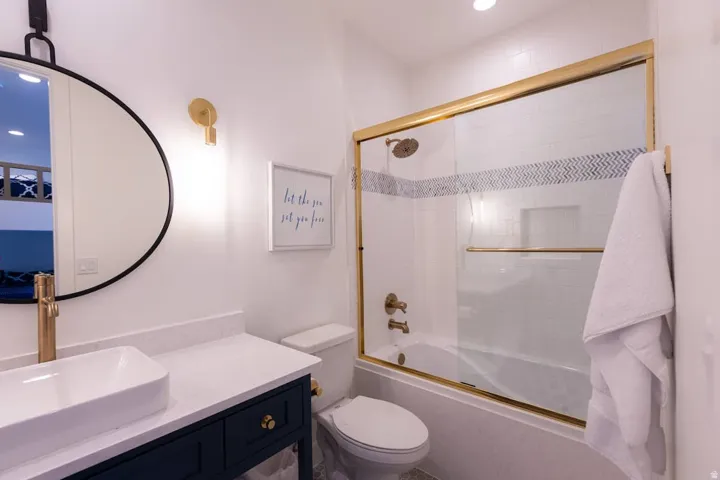 Bathroom with combined bath / shower with glass door, vanity, and recessed lighting