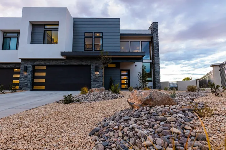 Modern home featuring stone siding, stucco siding, an attached garage, and concrete driveway