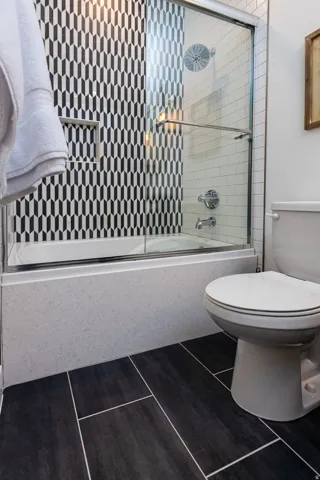 Full bath featuring combined bath / shower with glass door and dark tile patterned floors