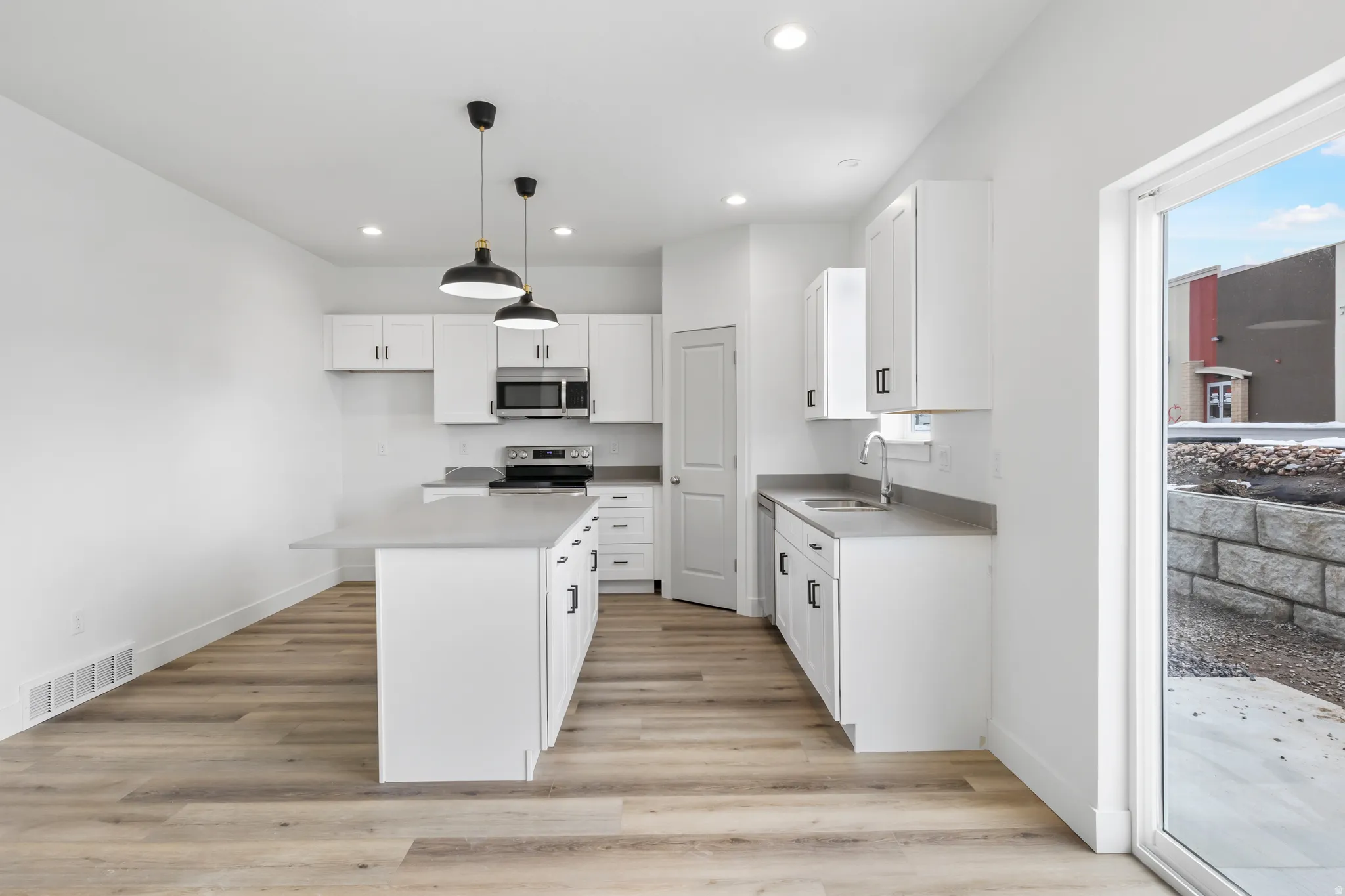 Kitchen with white cabinets, light countertops, and decorative light fixtures