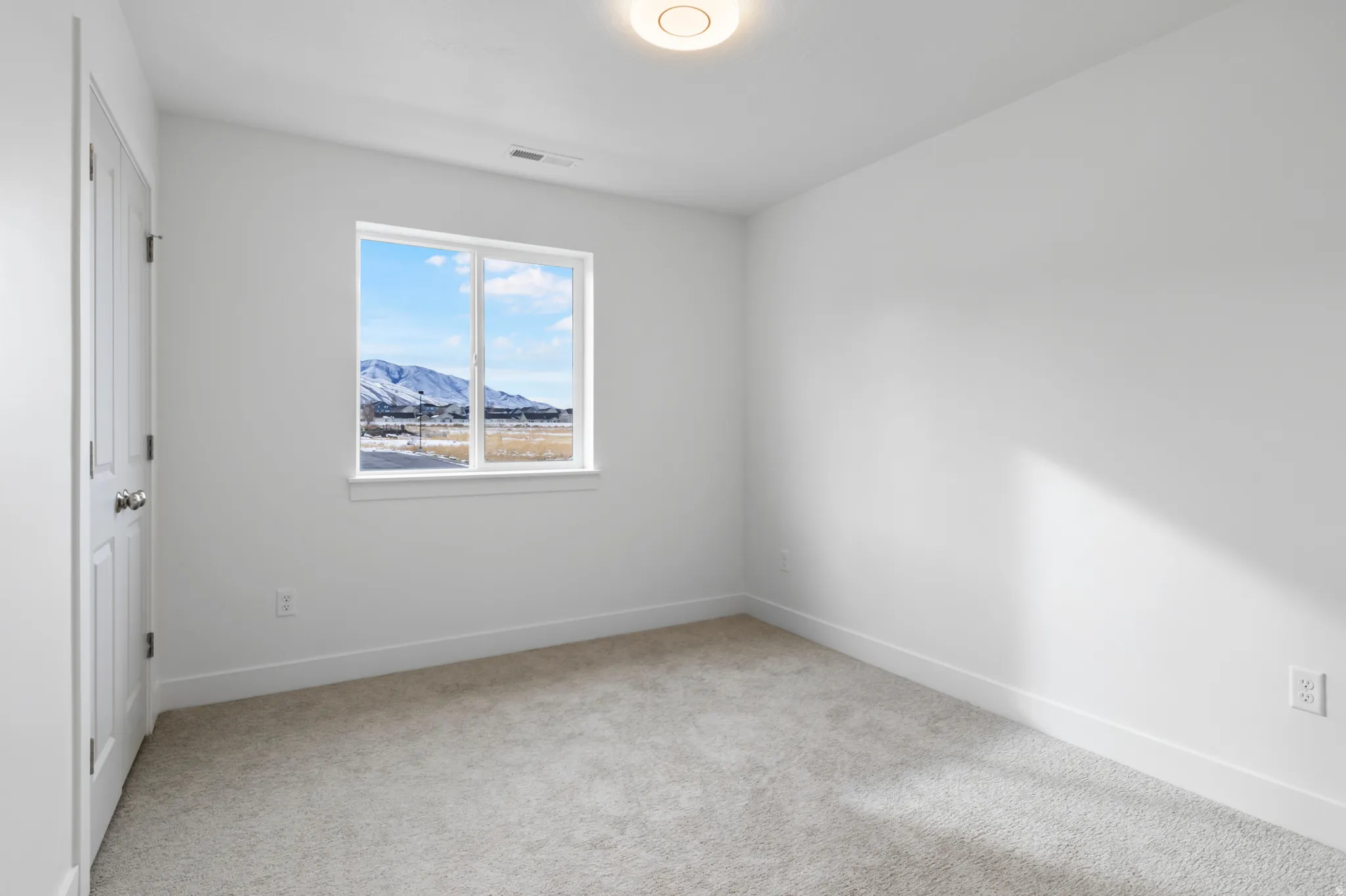 Unfurnished room with a mountain view and light colored carpet