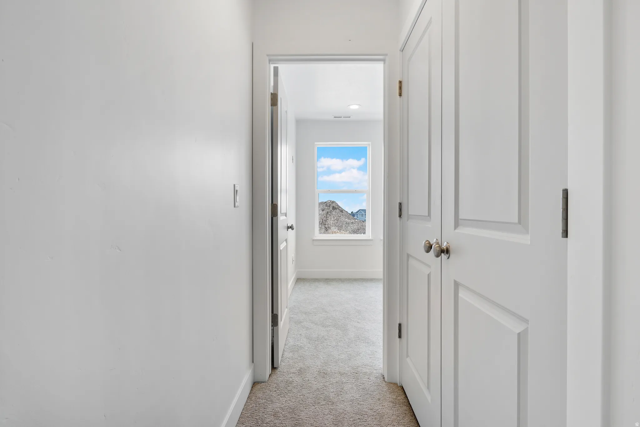 Corridor with light carpet and baseboards