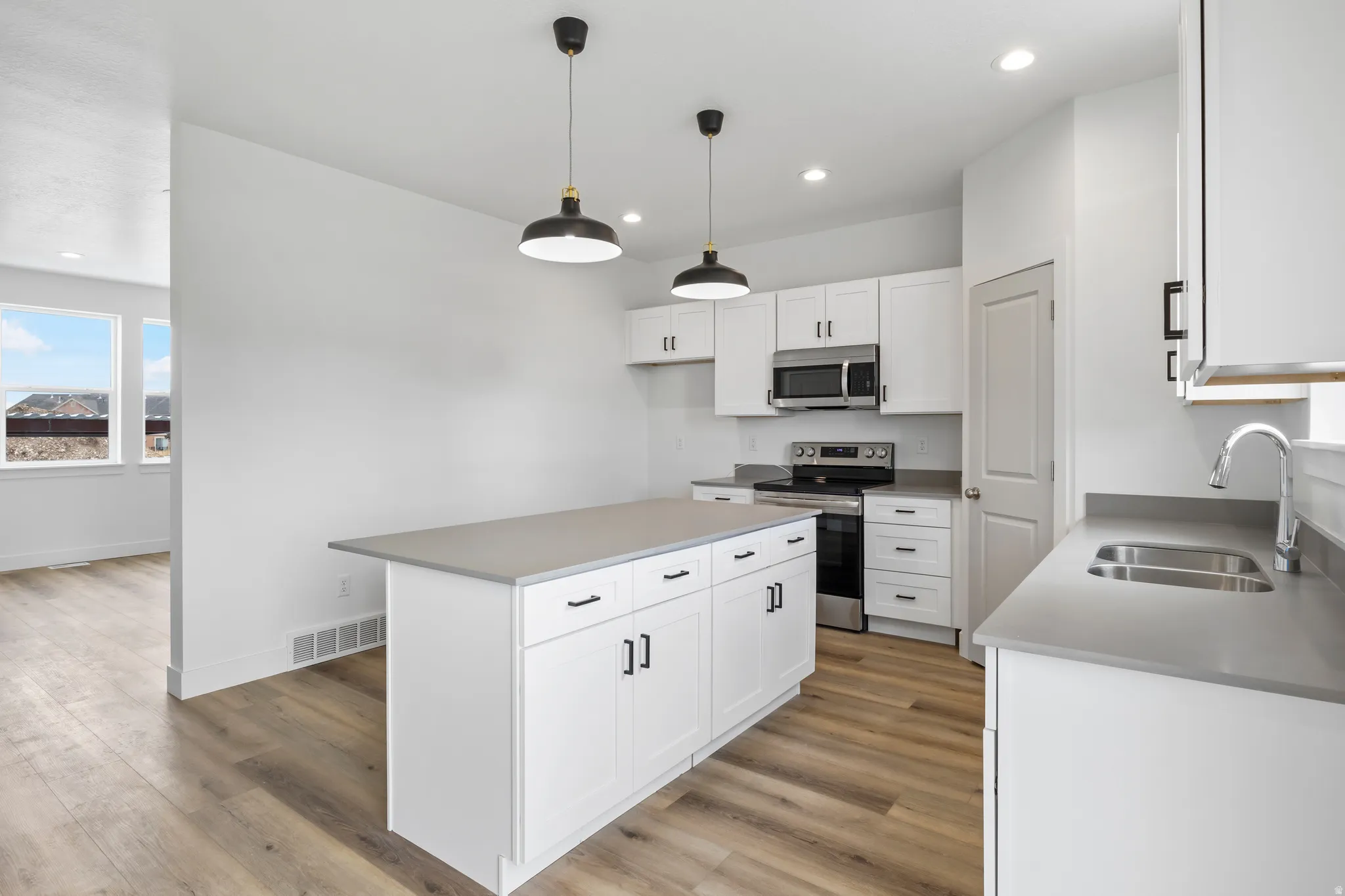Kitchen featuring stainless steel appliances, white cabinetry, a center island, and light wood-style flooring