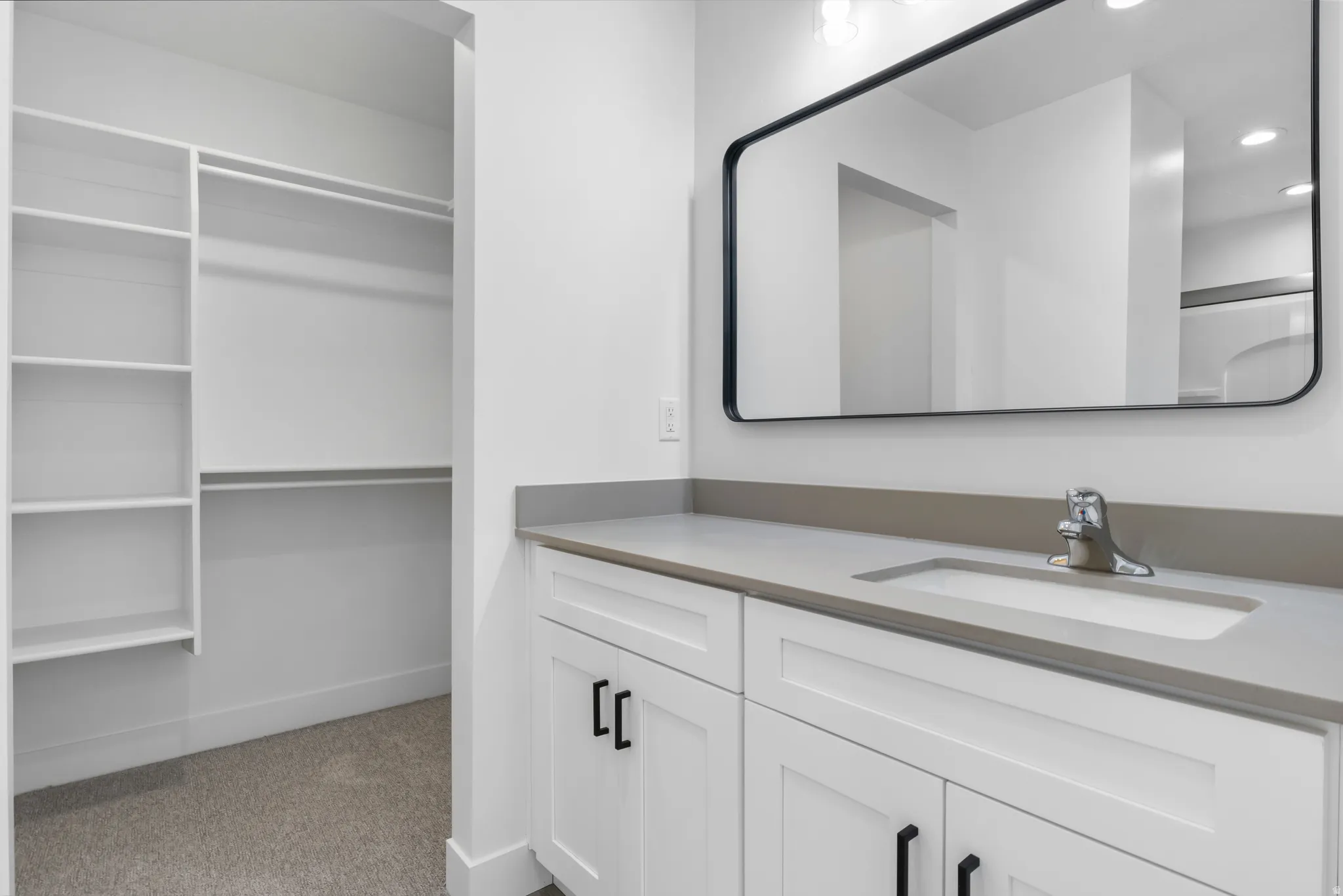 Bathroom with vanity, light carpet, recessed lighting, and a walk in closet