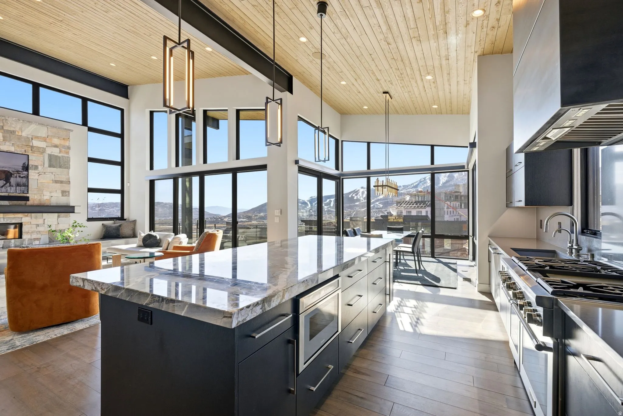 Dual tone kitchen with decorative light fixtures, two tone color scheme, dark wood-style flooring, stainless steel appliances, and a fireplace