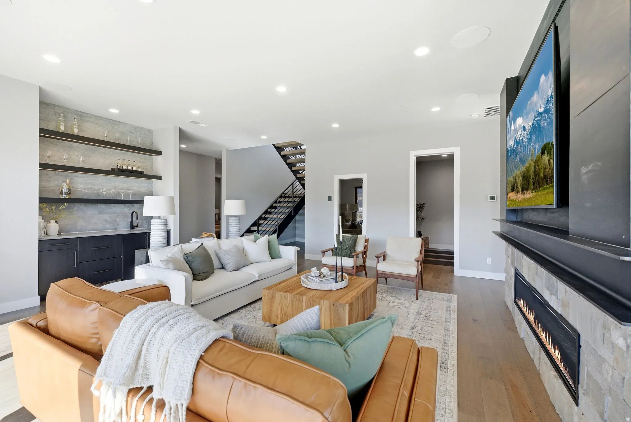 Living area with wood-type flooring, a large fireplace, wet bar, and recessed lighting