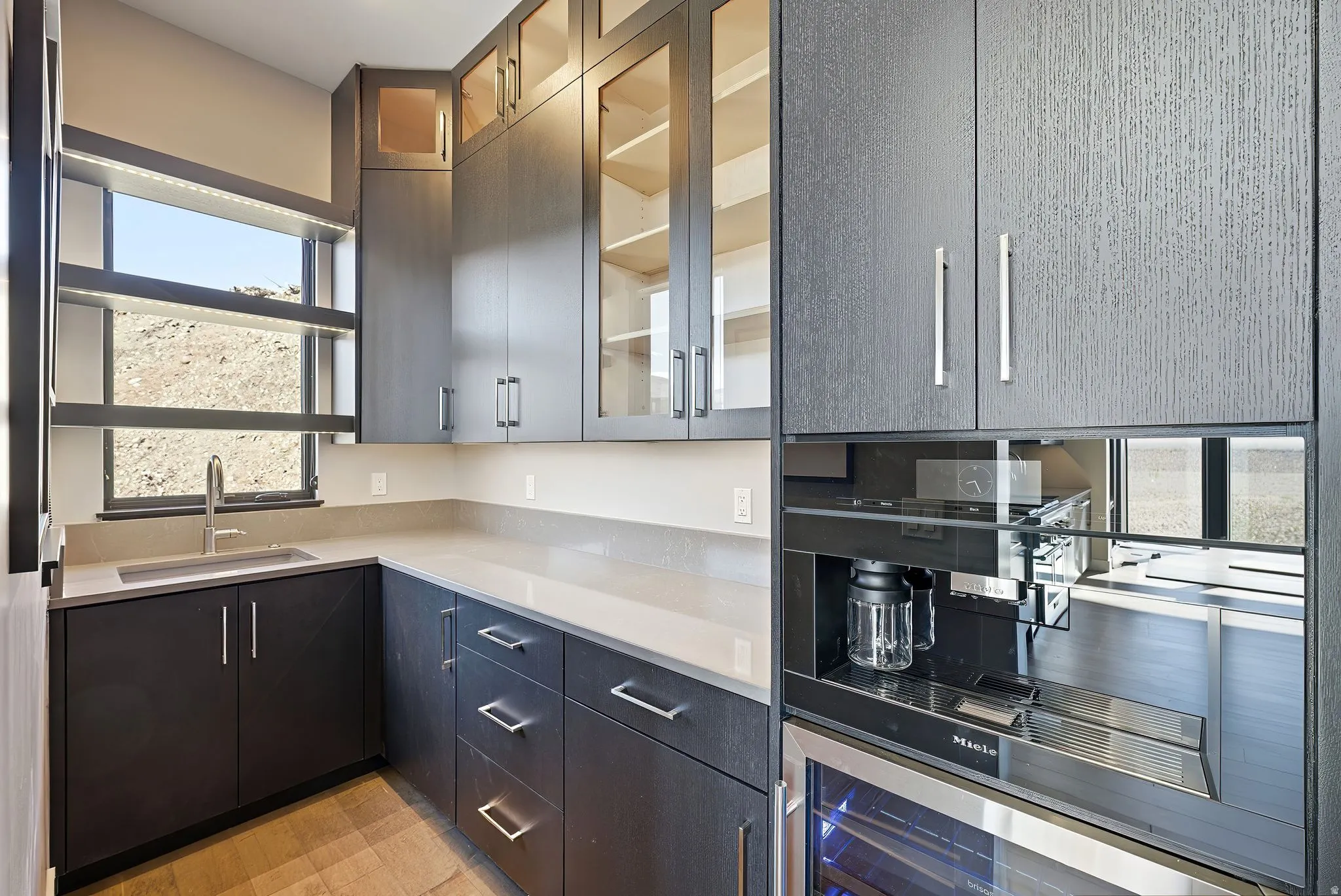 Kitchen featuring glass fronted cabinets, light stone counters, and beverage cooler