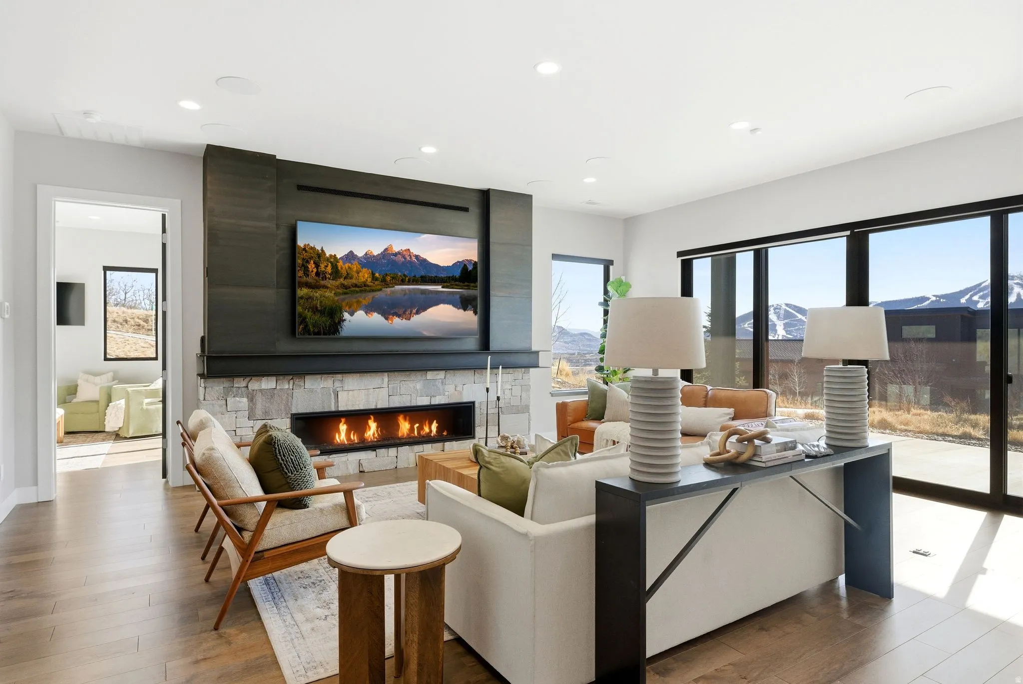Living area featuring a stone fireplace, light wood-type flooring, plenty of natural light, and recessed lighting