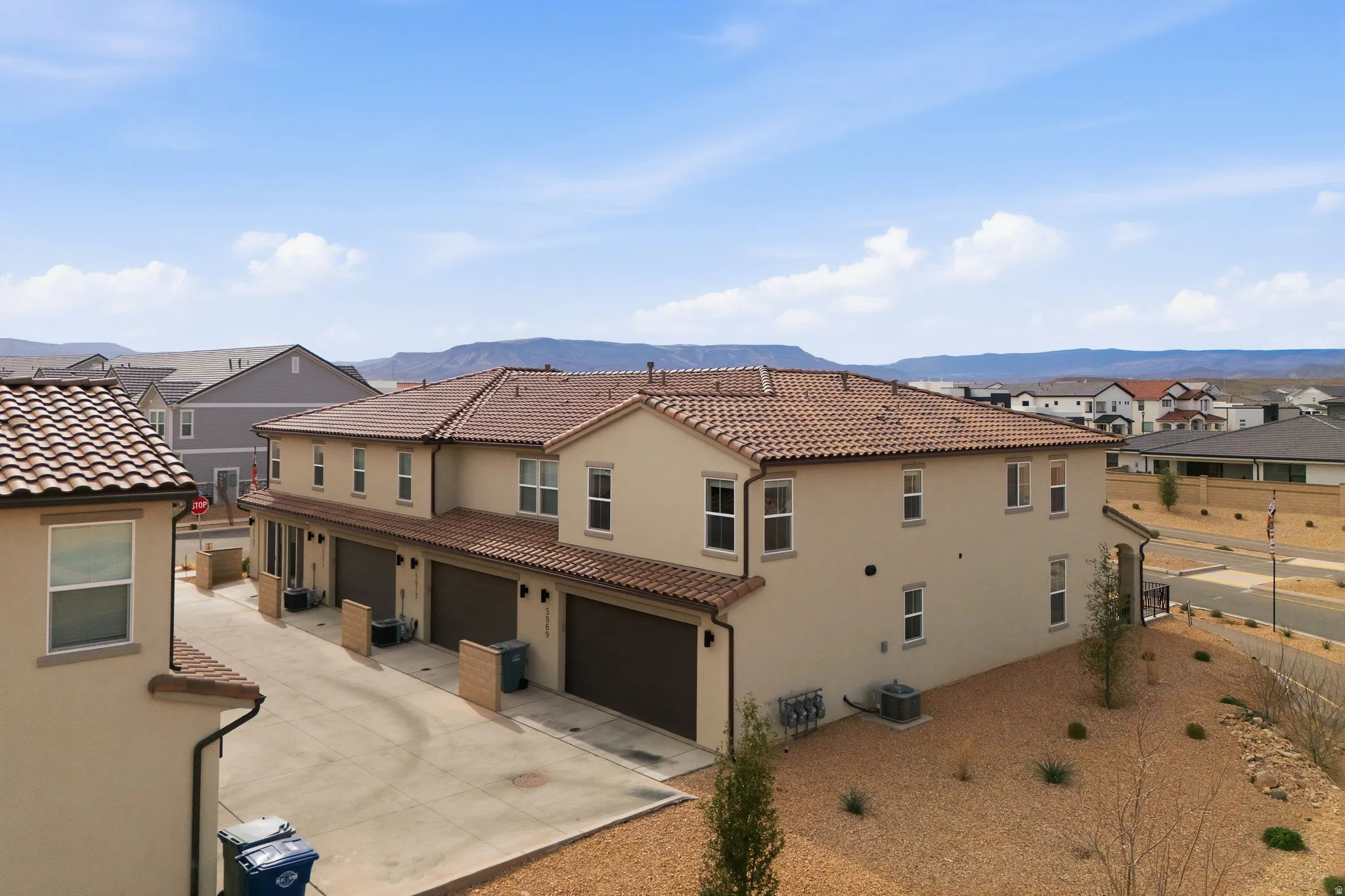 Rear view of house featuring a garage, stucco siding, a residential view, driveway, and a tiled roof