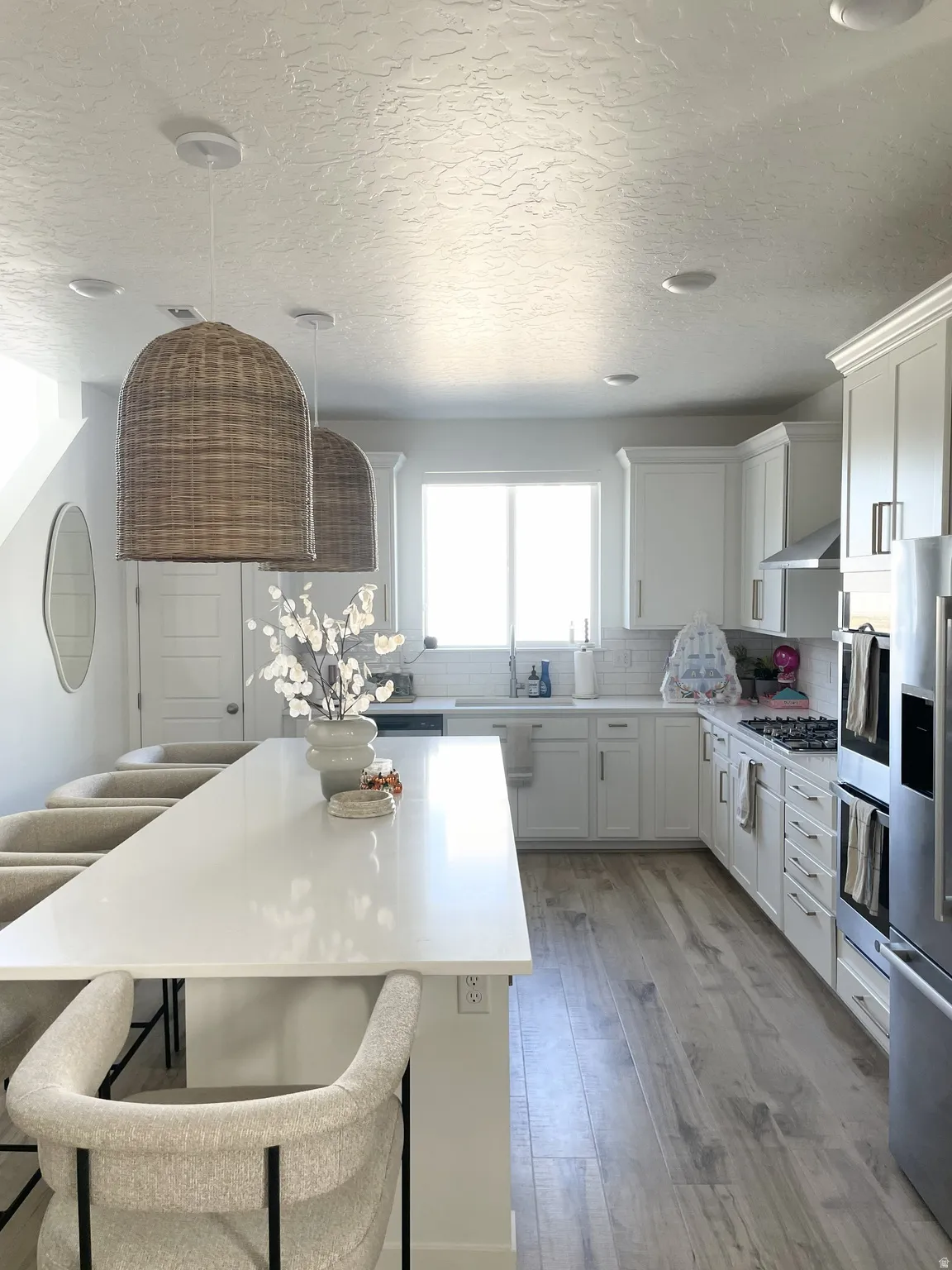 Kitchen with a breakfast bar area, white cabinetry, tasteful backsplash, light wood finished floors, and stainless steel appliances