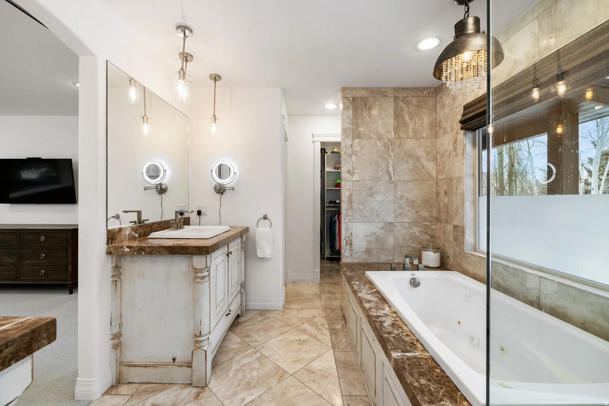 Bathroom featuring a whirlpool tub, vanity, and a spacious closet