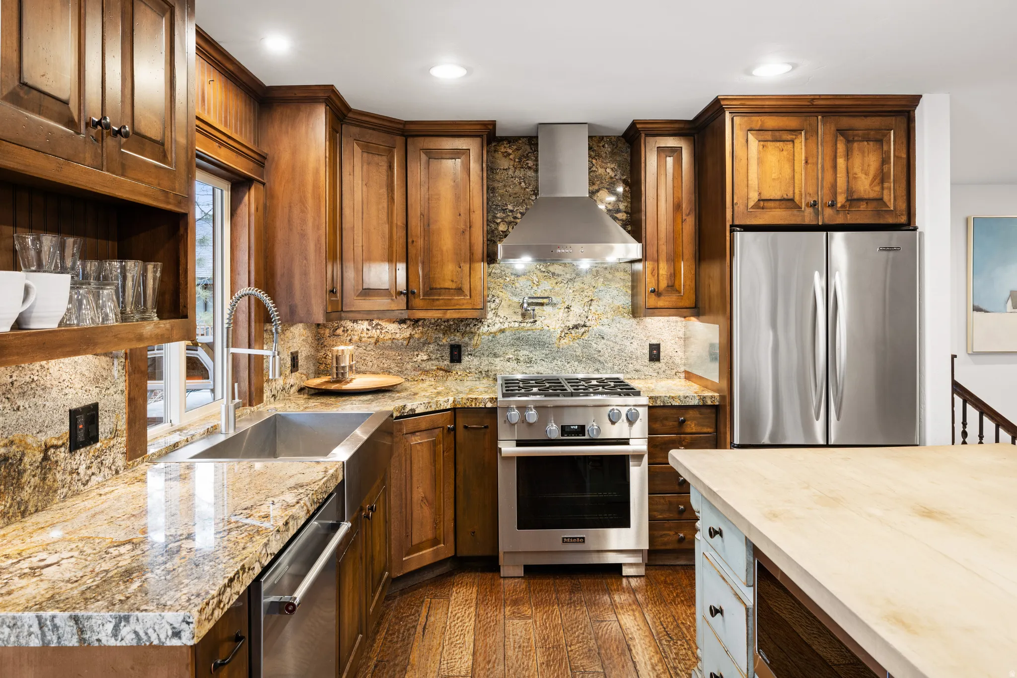 Two tone kitchen featuring decorative backsplash, stainless steel appliances, dark wood-type flooring, light stone counters, and dual tone cabinets