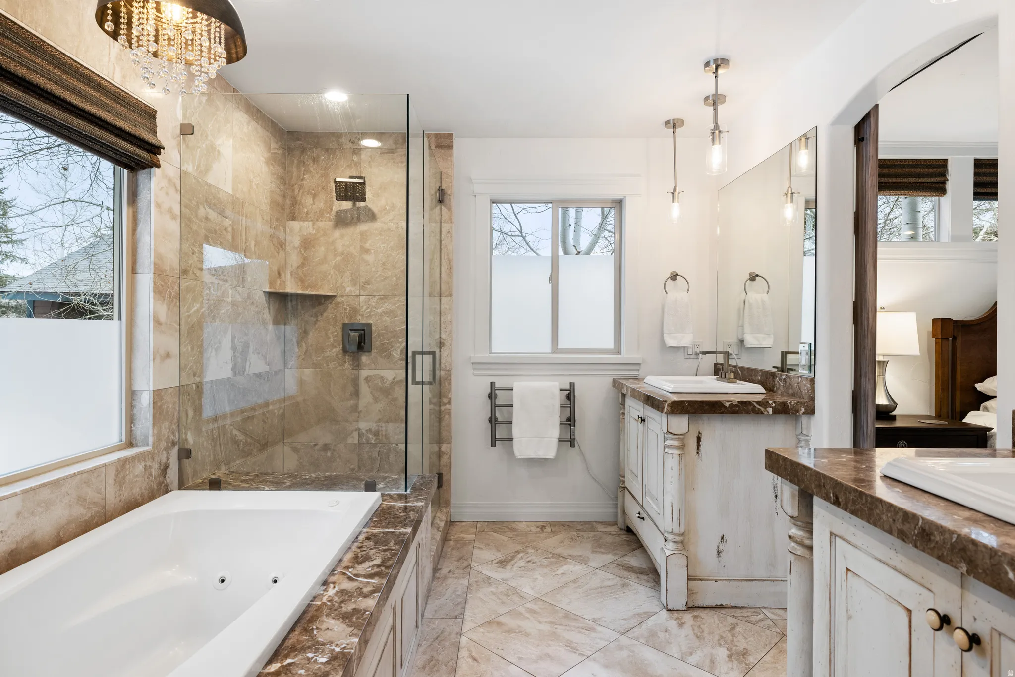 Full bath featuring a jetted tub, two vanities, and a stall shower