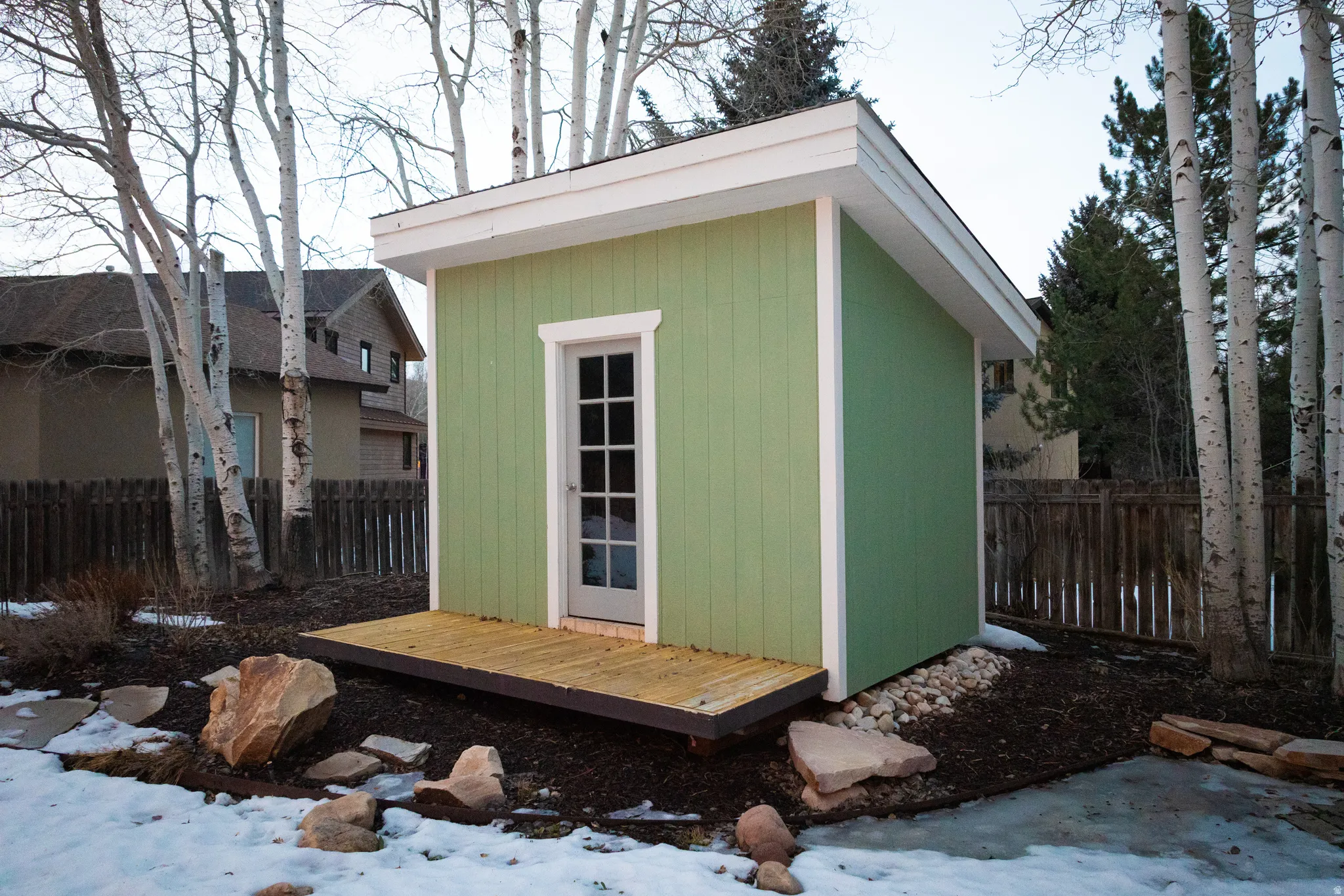 Snow covered structure with a fenced backyard and a storage shed