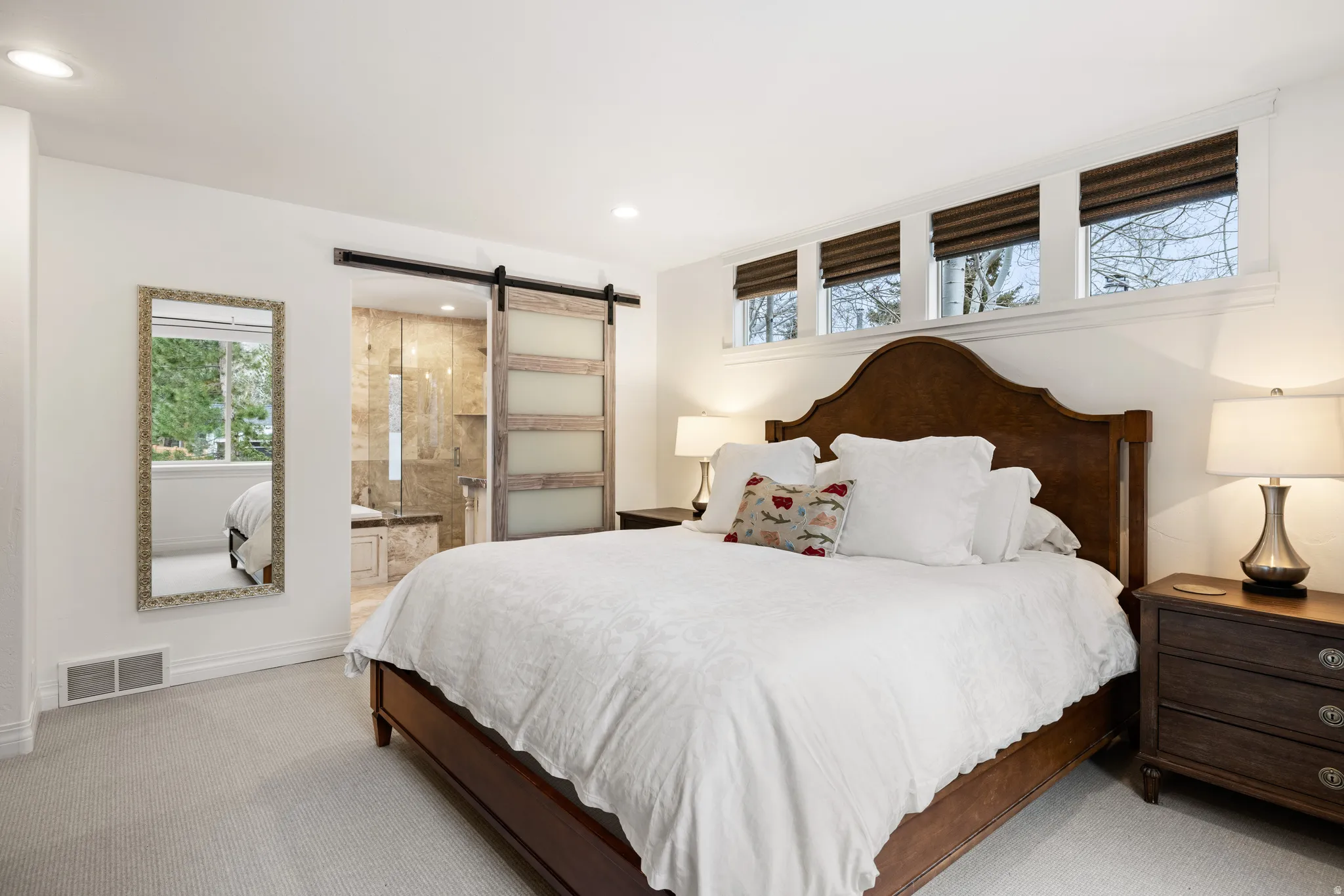 Bedroom with a barn door, carpet floors, connected bathroom, and recessed lighting