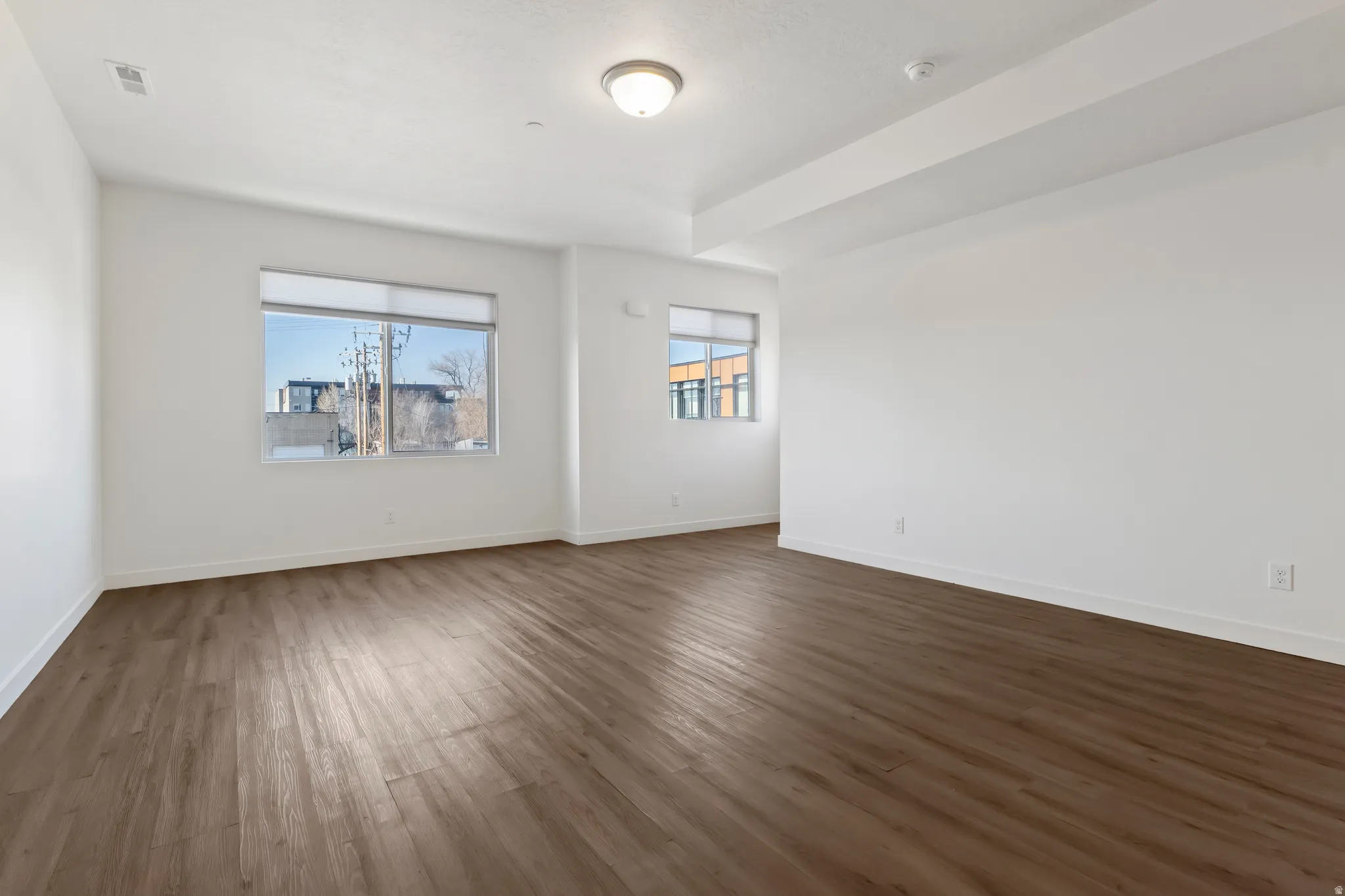 Unfurnished room featuring dark wood-style flooring and baseboards