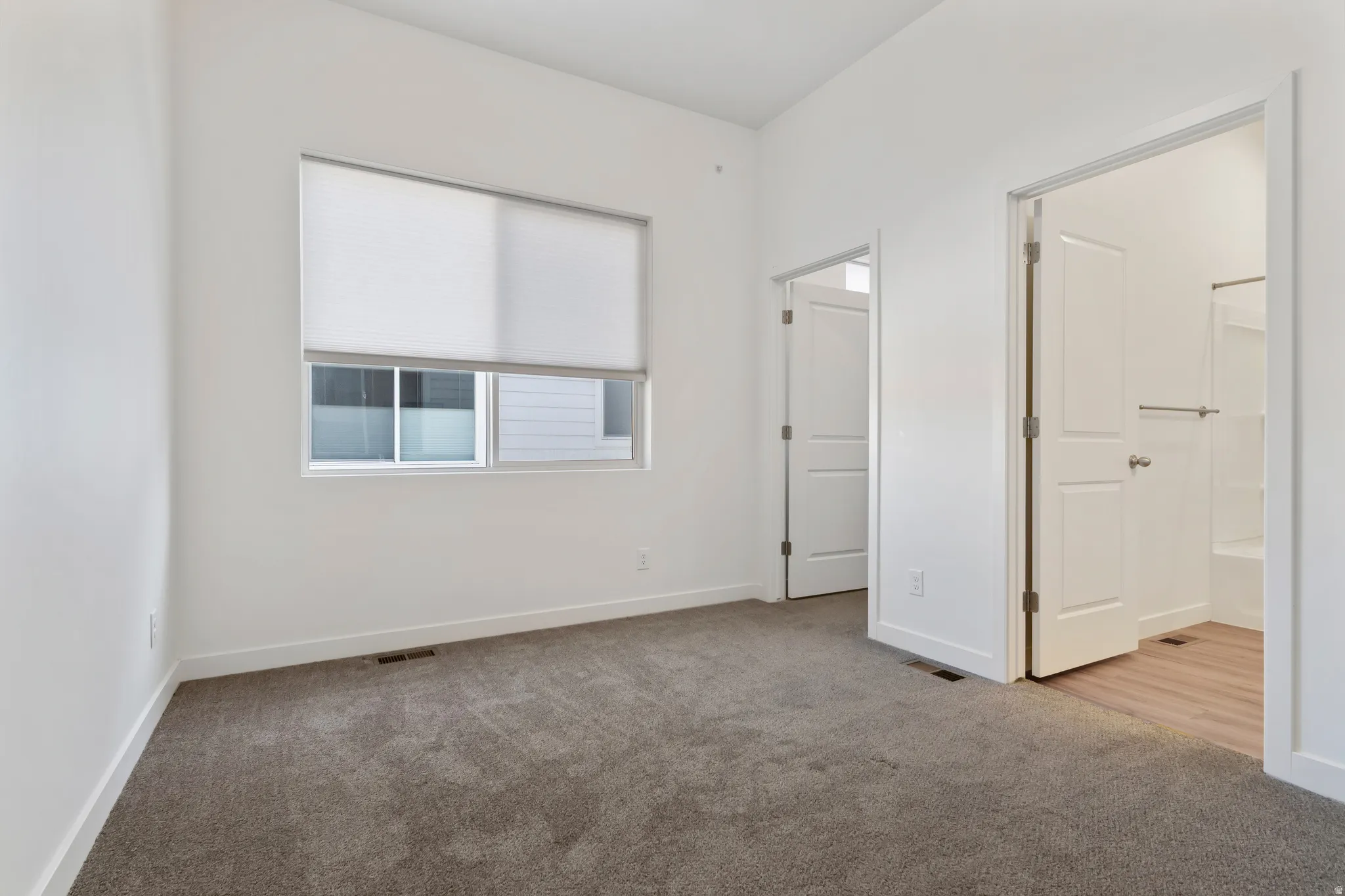 Unfurnished bedroom featuring light colored carpet and baseboards