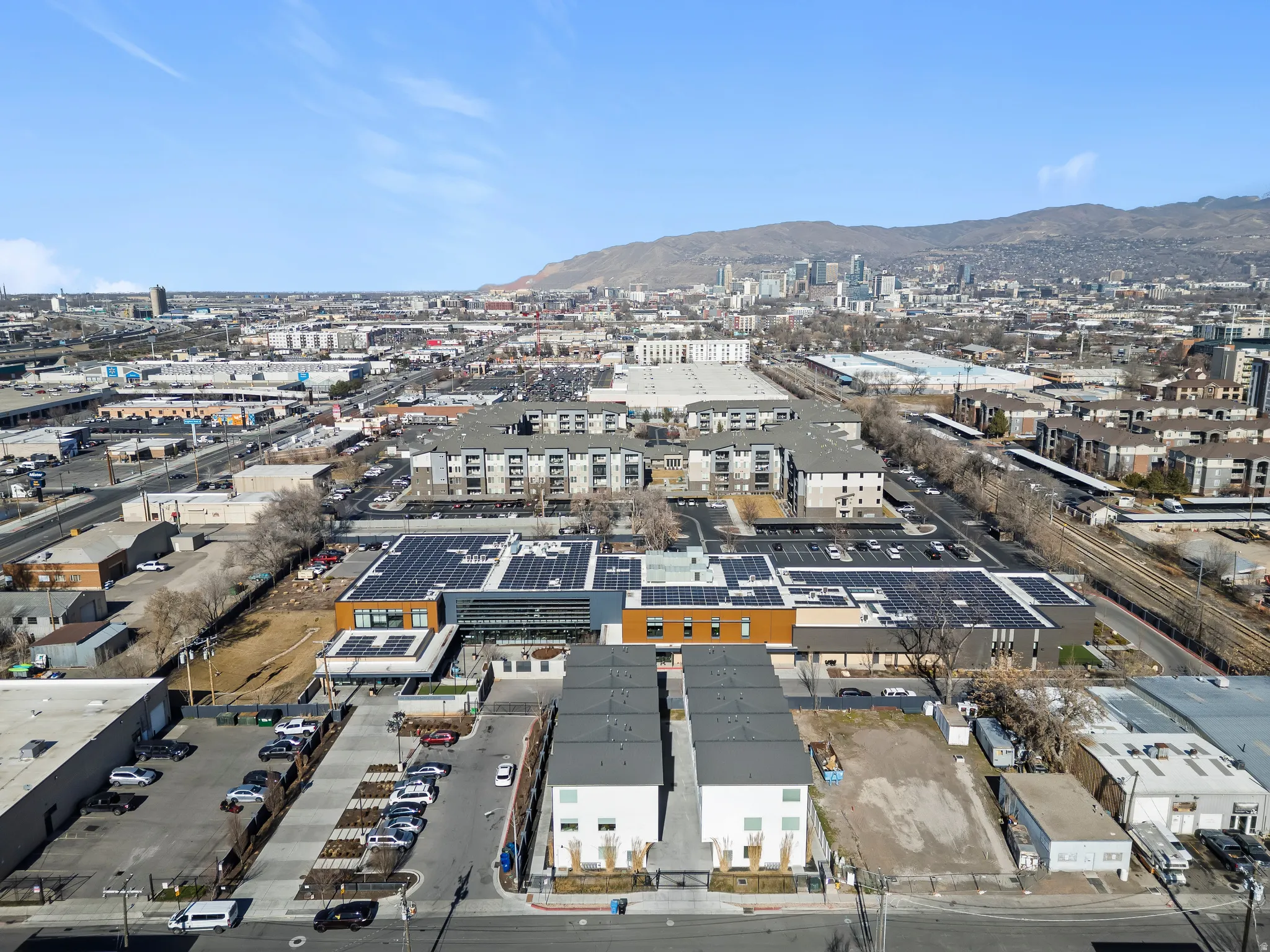 Aerial view of property and surrounding area featuring industrial structures and a mountainous background