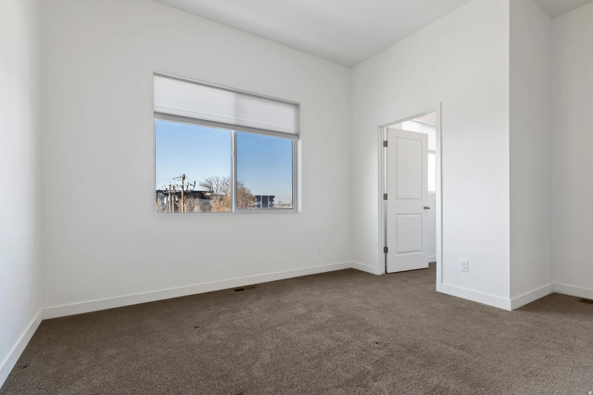 Spare room with dark carpet and baseboards