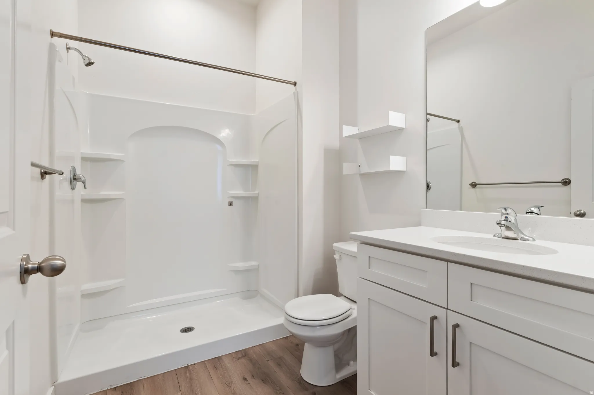 Bathroom with a stall shower, light wood-style flooring, and vanity