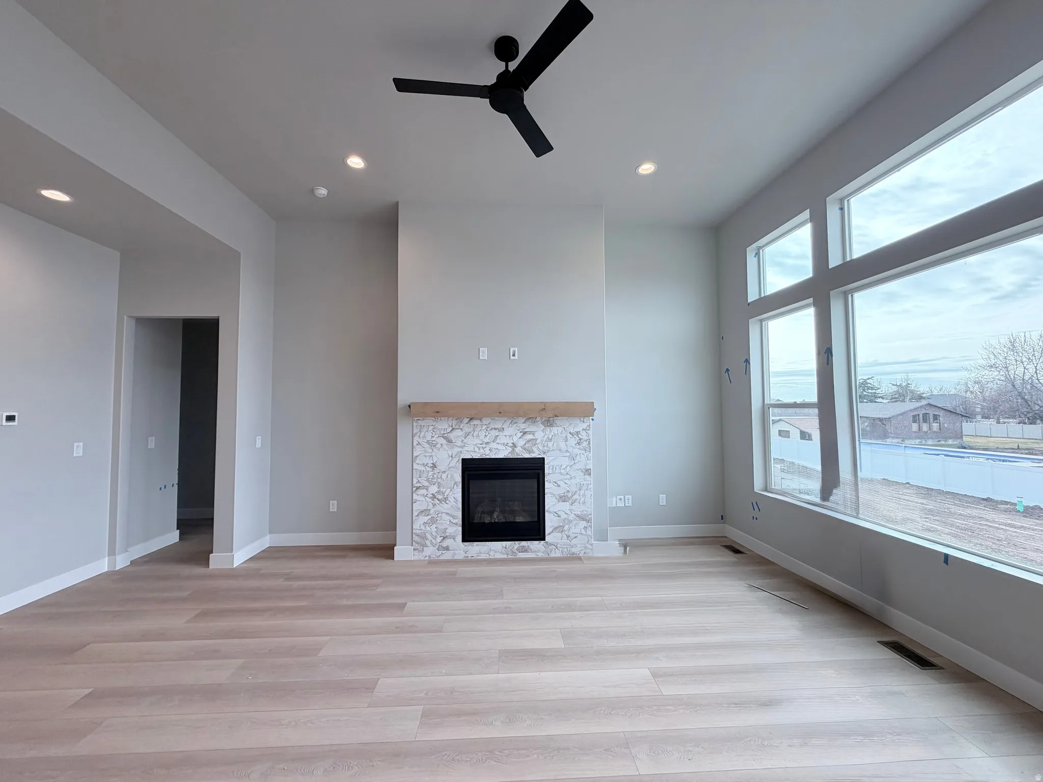 Unfurnished living room with ceiling fan, a glass covered fireplace, light wood-style flooring, and recessed lighting