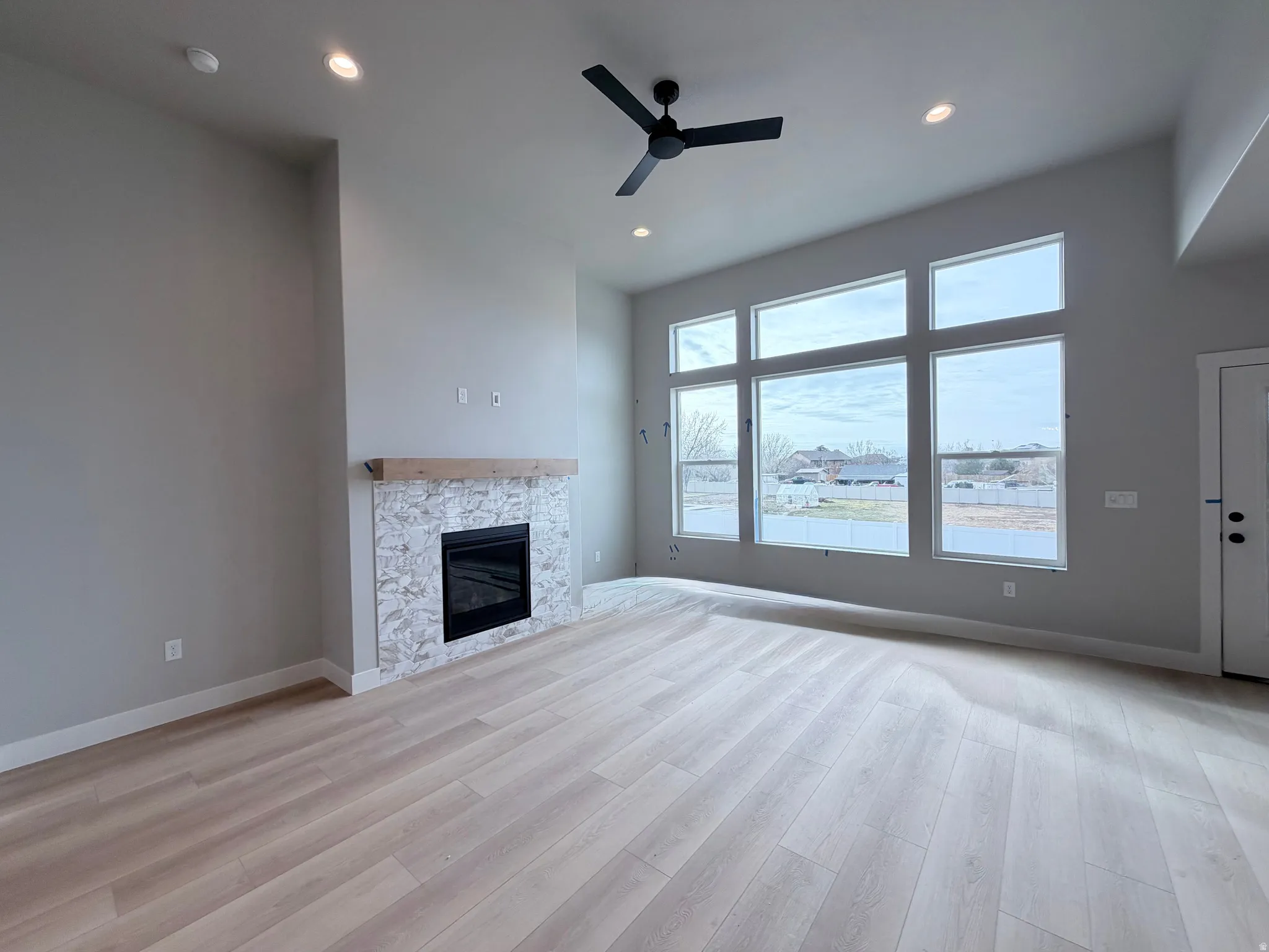 Unfurnished living room with ceiling fan, light wood-style flooring, a fireplace, and recessed lighting