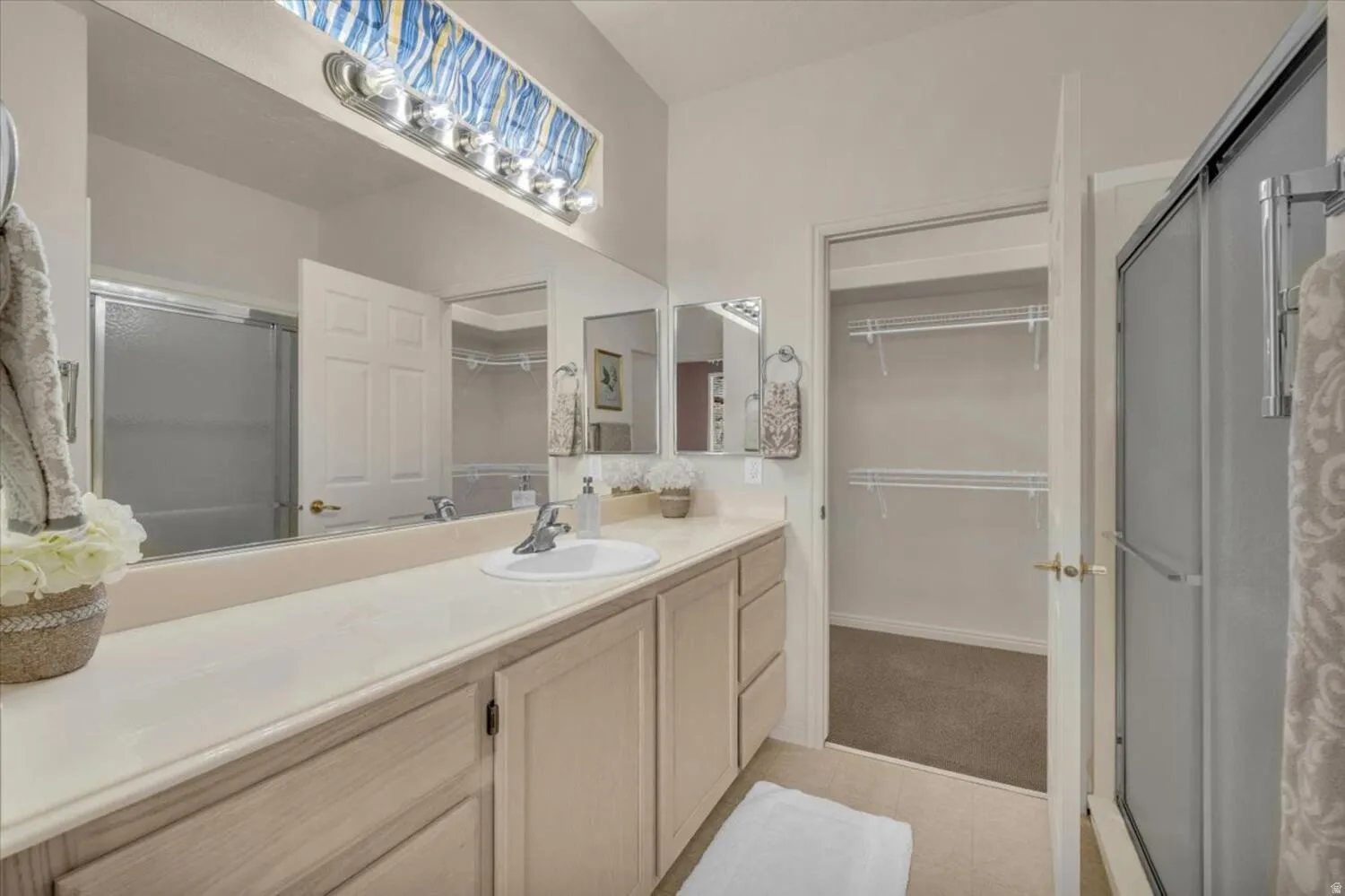 Full bath with a spacious closet, a stall shower, and vanity