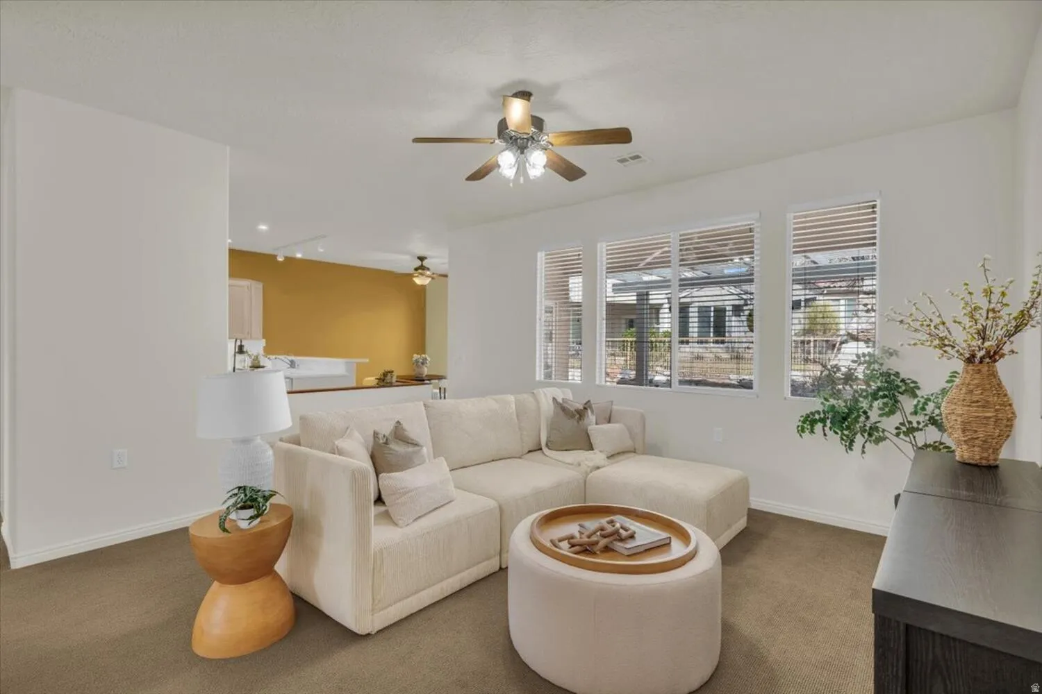 Carpeted living room featuring baseboards and a ceiling fan